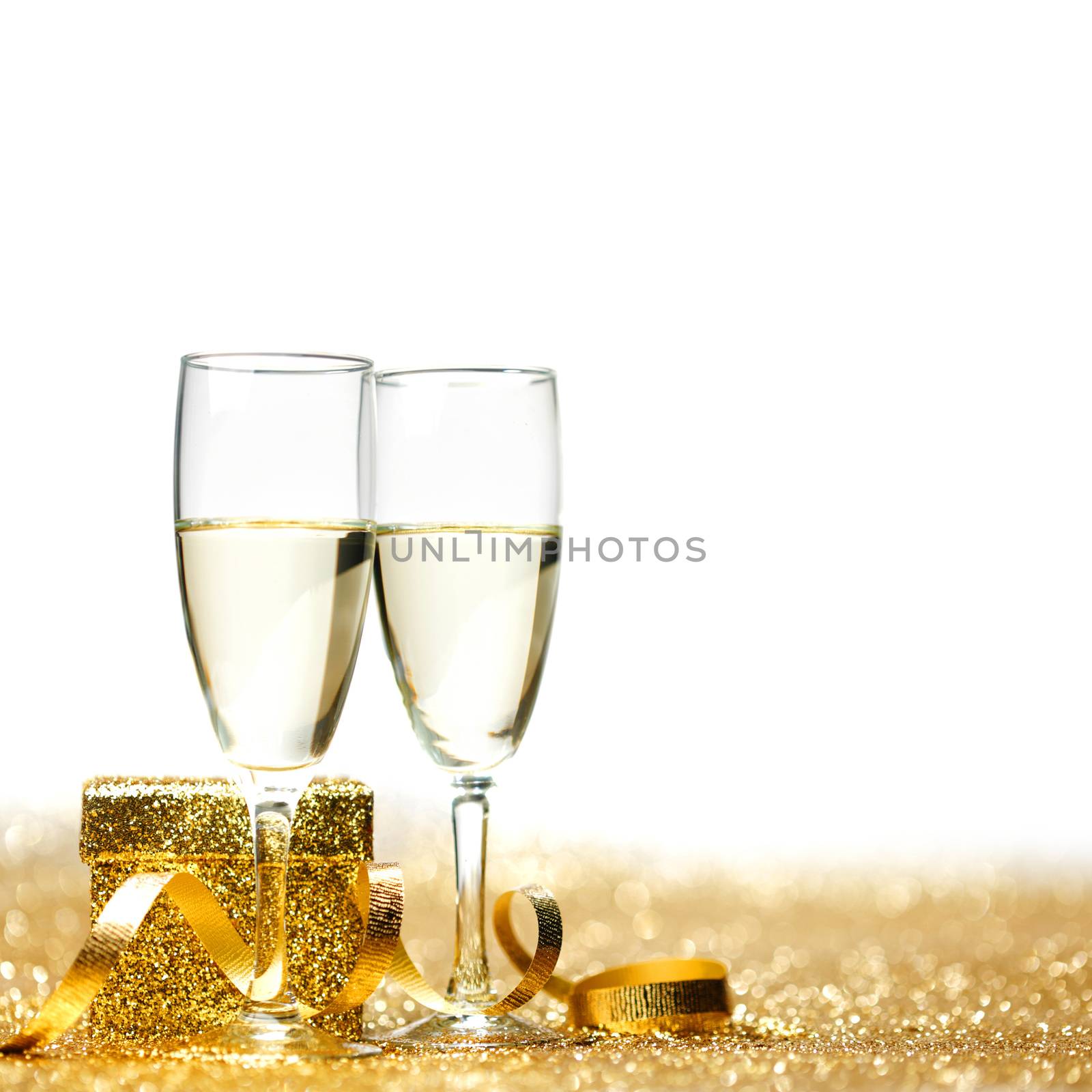 Champagne in glasses and gift box on golden background