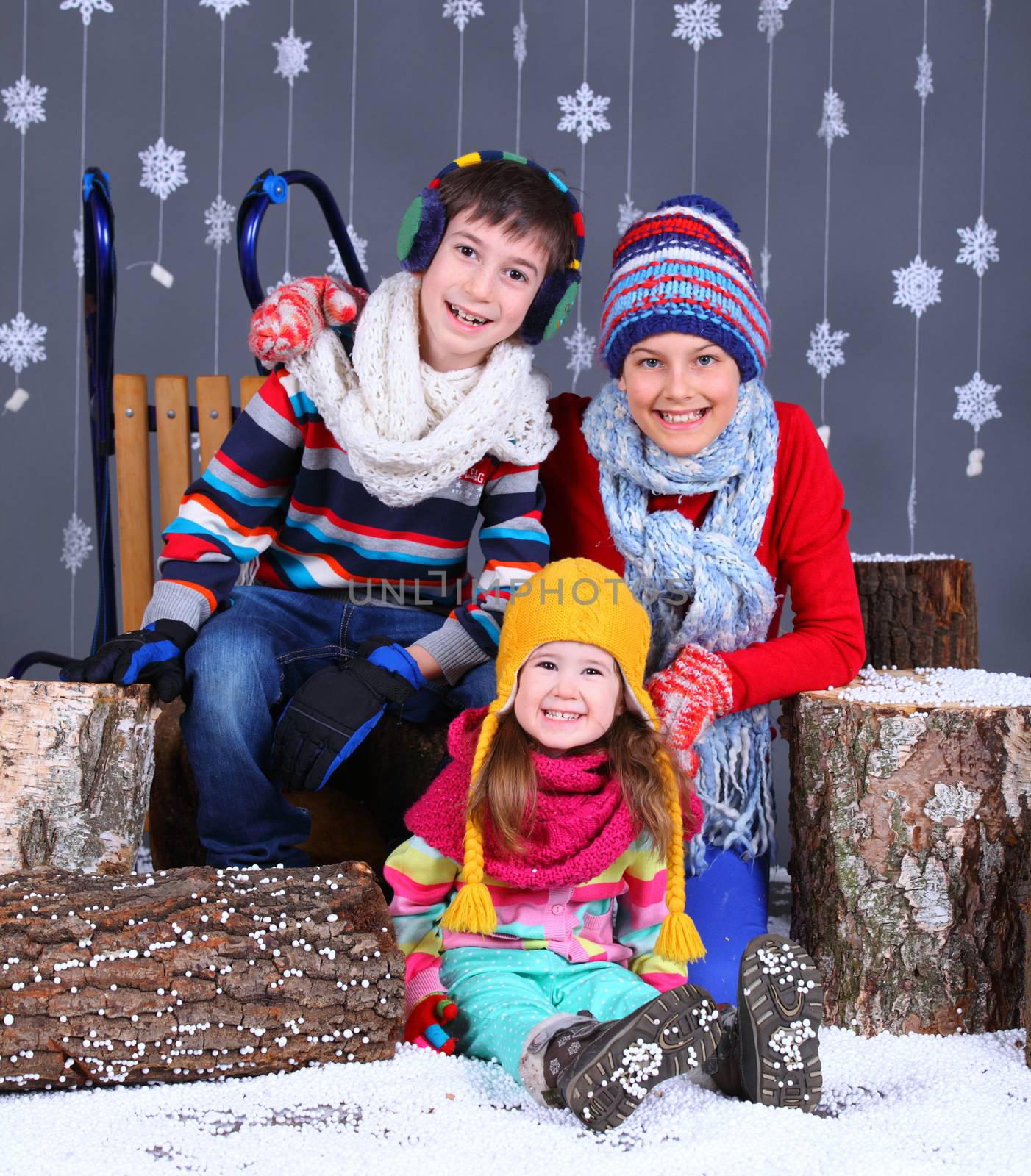 Winter Fashion. Adorable happy boy and girls in winter hat, gloves and sweater in studio.