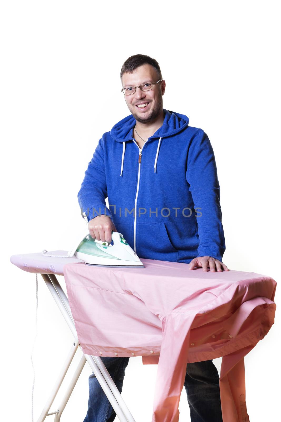 Happy man doing housework and ironing a shirt
