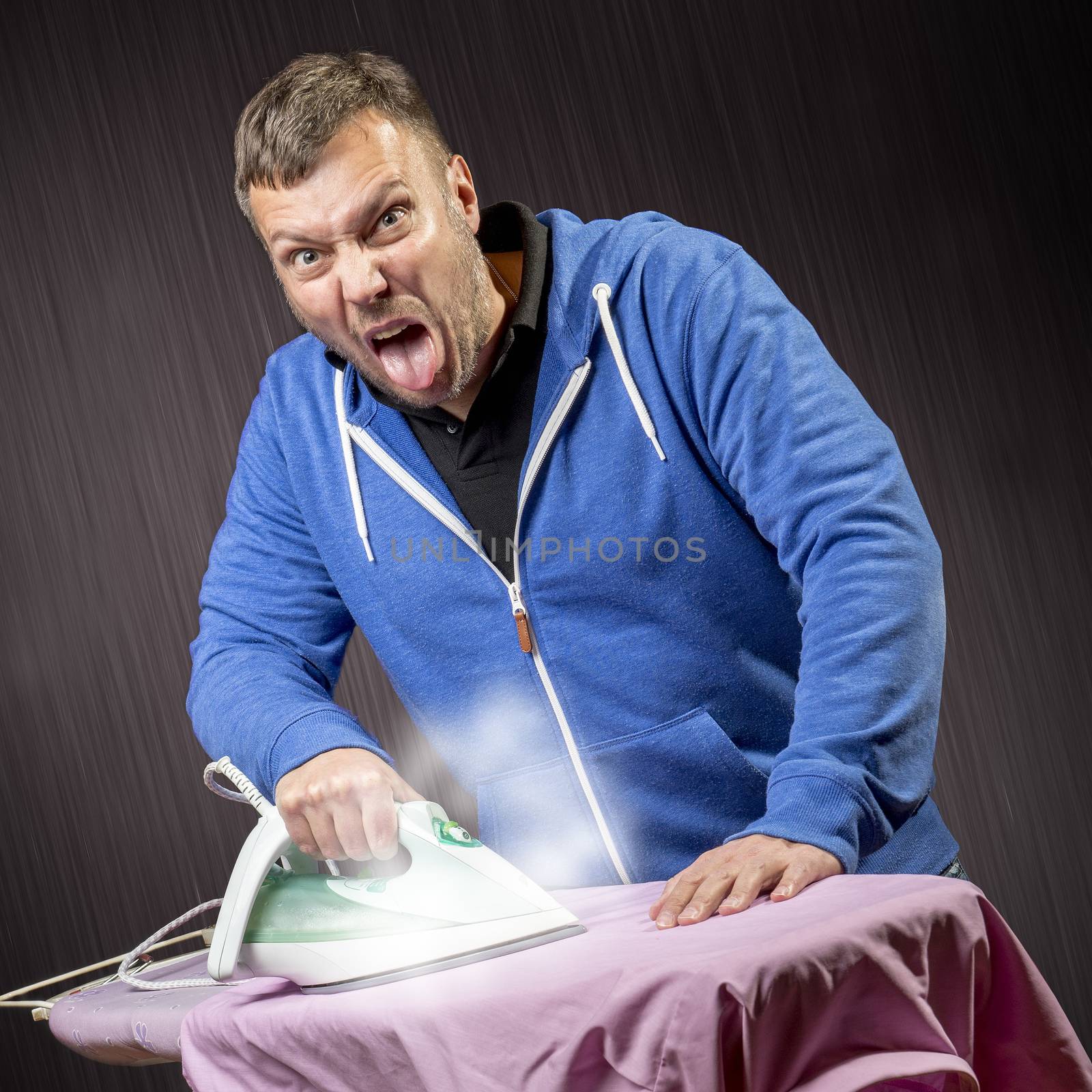 Angry man doing housework and ironing a shirt
