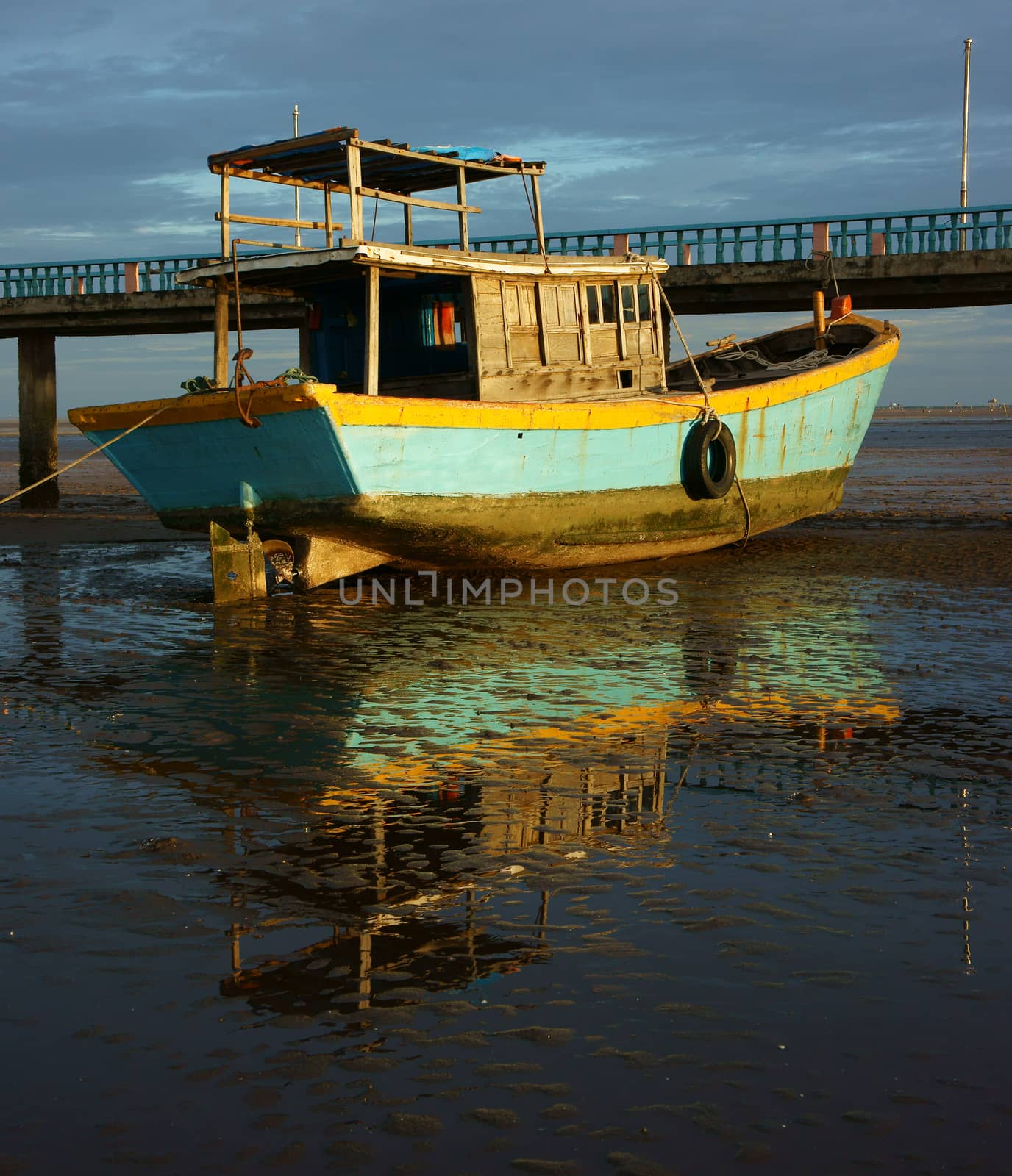 Harmony landscape of colorful view, wooden fishing boat reflect shadow on water, tide going out let black sand and hold of boat, cloud sky, brilliant color and amazing reflection