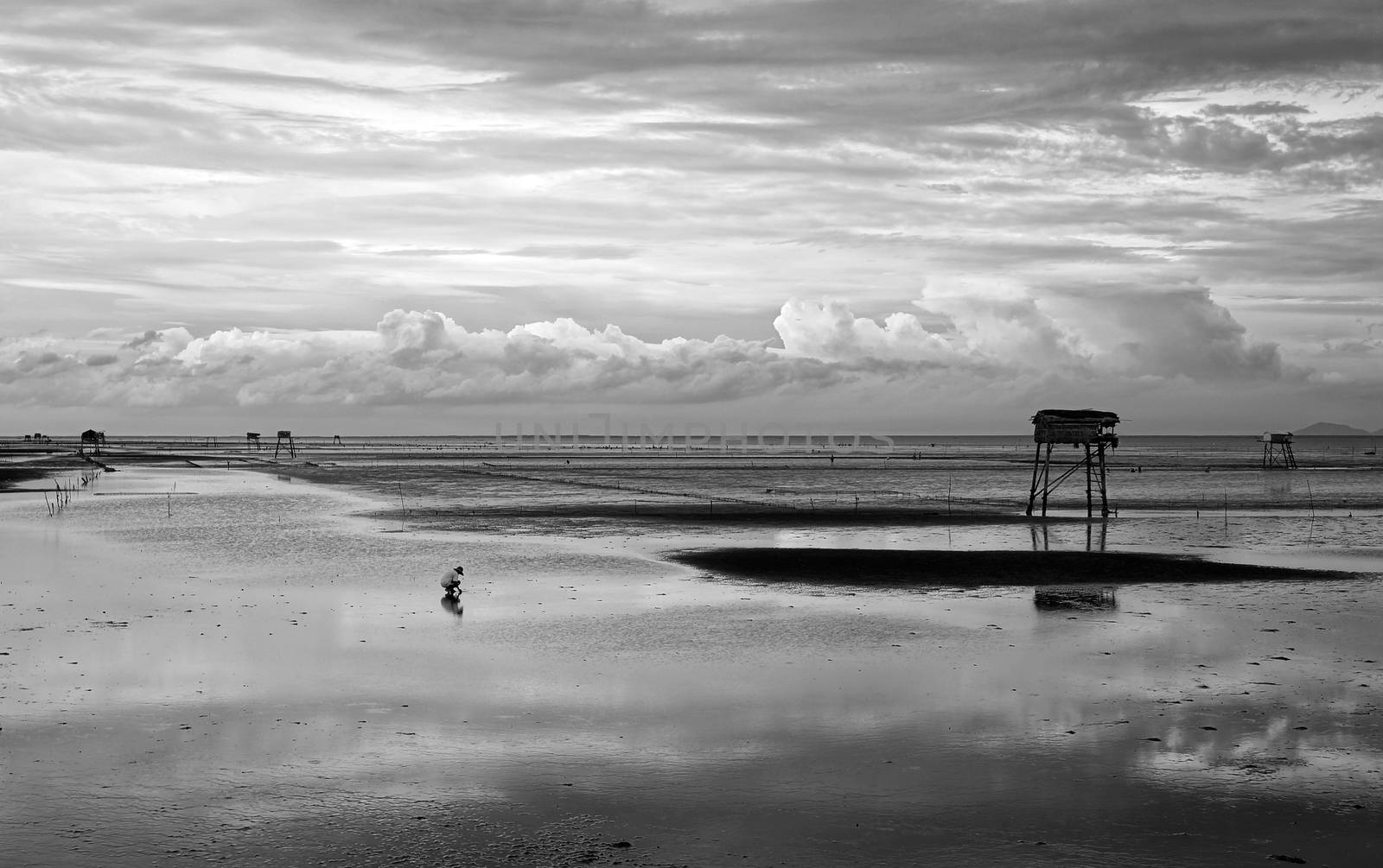 Abstract scene lonely man on Vietnam beach under cloudy sky, watch tower on black sand at Mekong Delta beach 