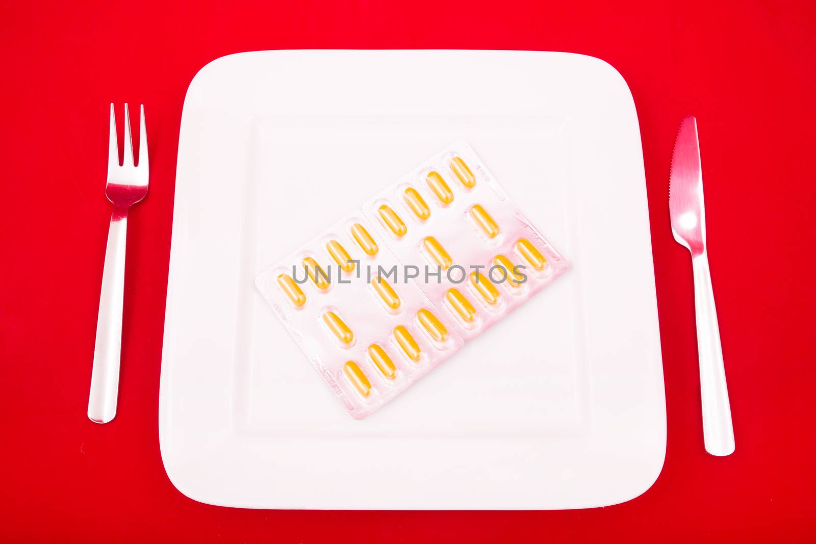 A white plate with medicine on red background.
