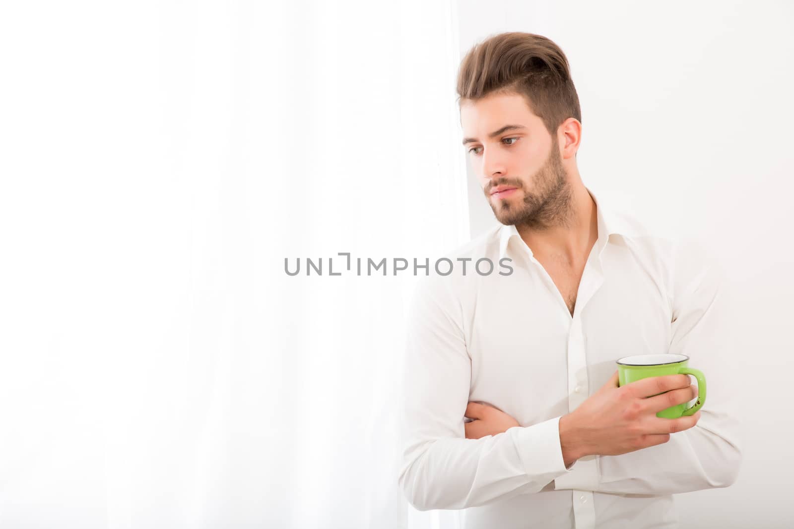 A young adult man at home drinking coffee.