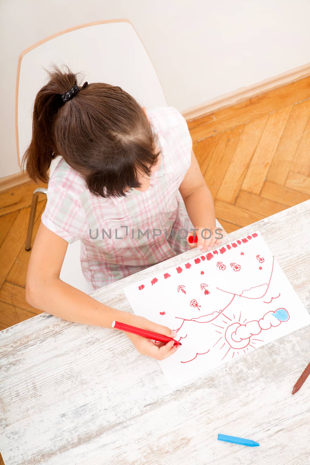 A daughter drawing at the table at home.
