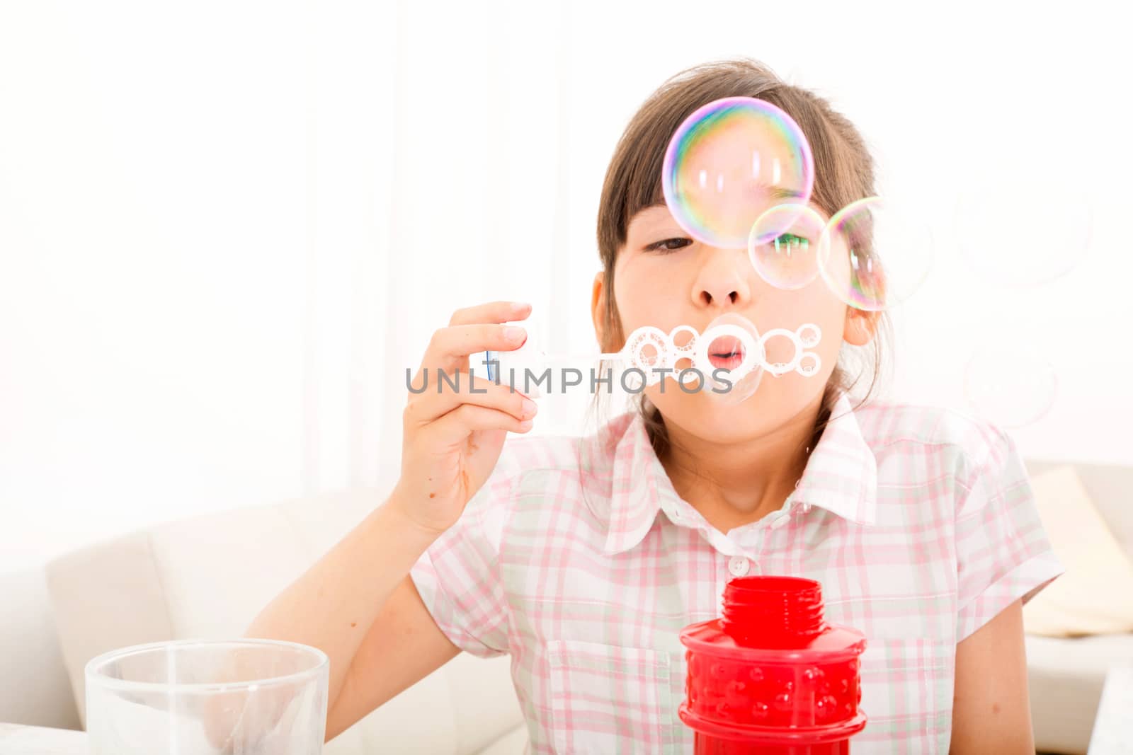 Portrait of girl blowing bubbles at home at the table.
