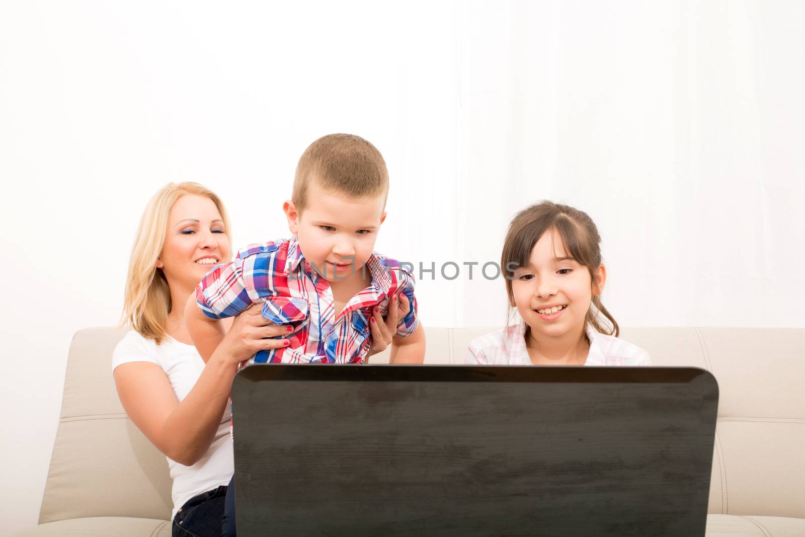 A mother using with her son and daughter a laptop computer.
