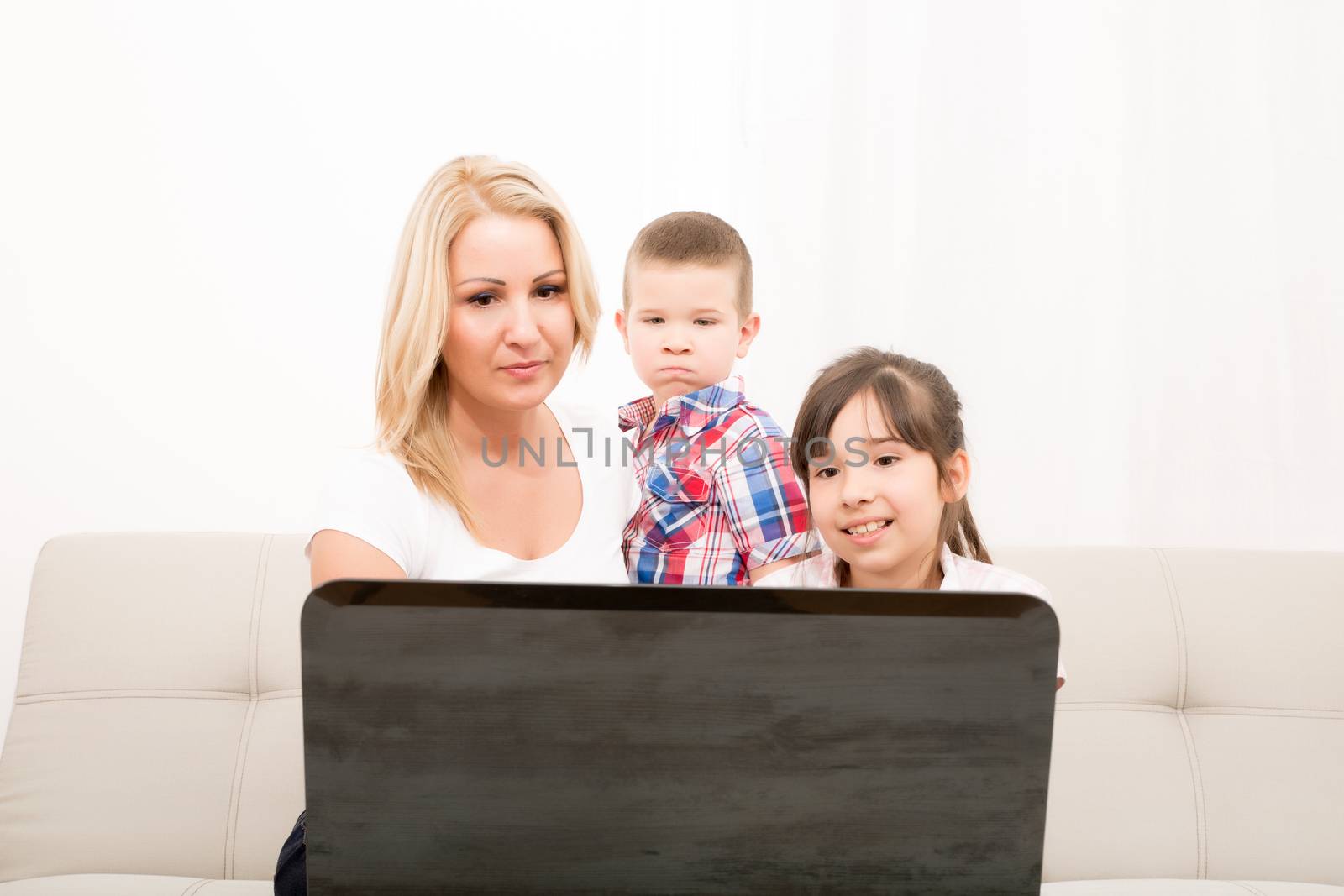 A mother using with her son and daughter a laptop computer.