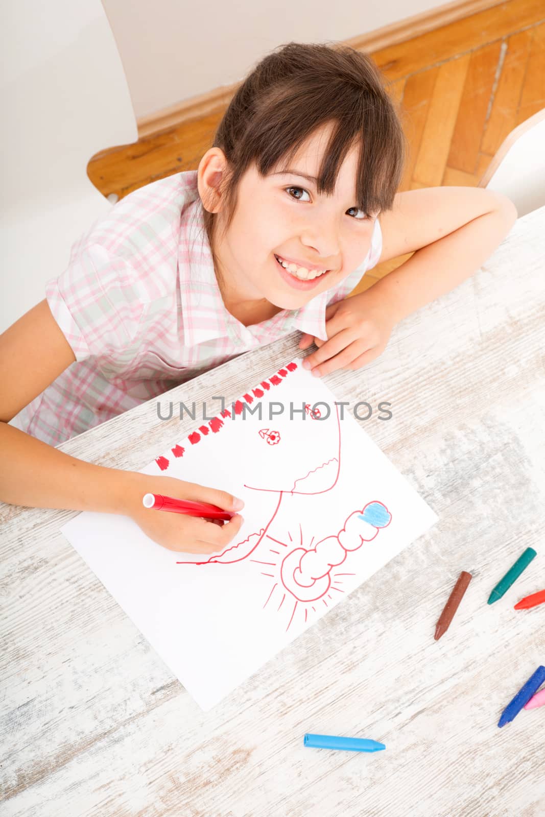 A daughter drawing at the table at home.
