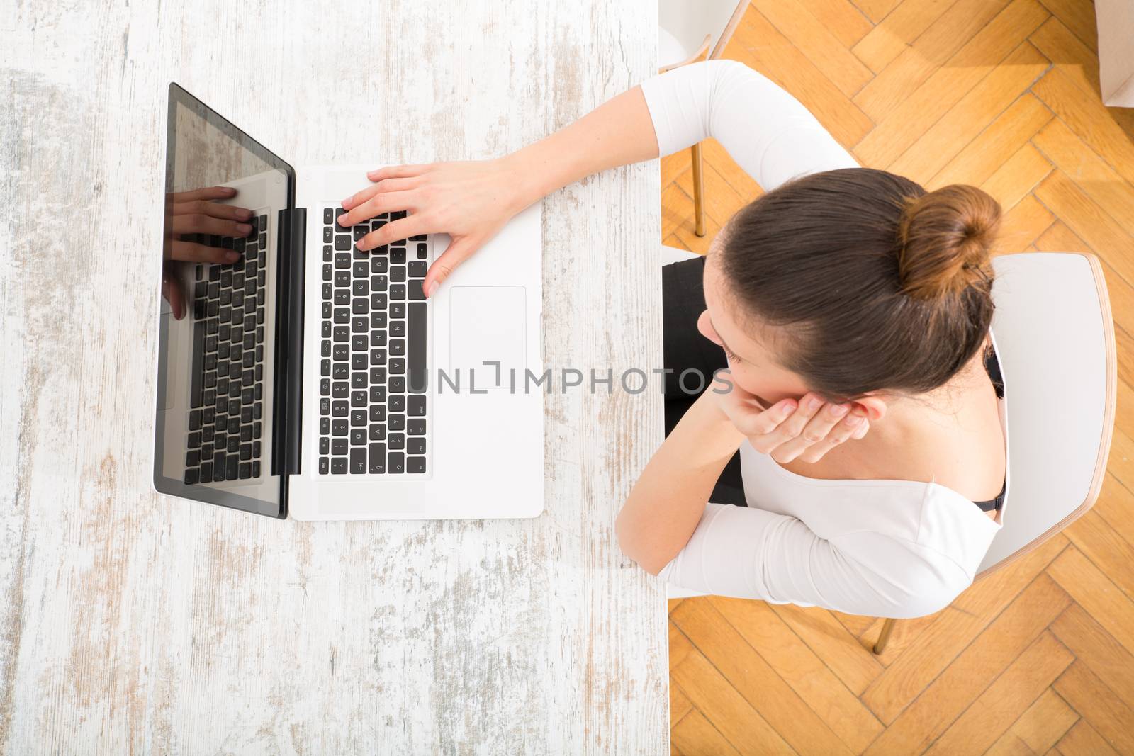 A young adult woman working on a laptop.
