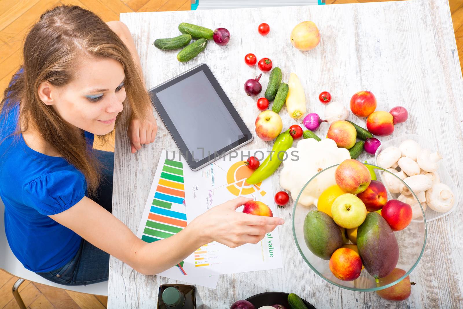 A young adult woman informing herself with a tablet PC about nutritional values of fruits and vegetables.