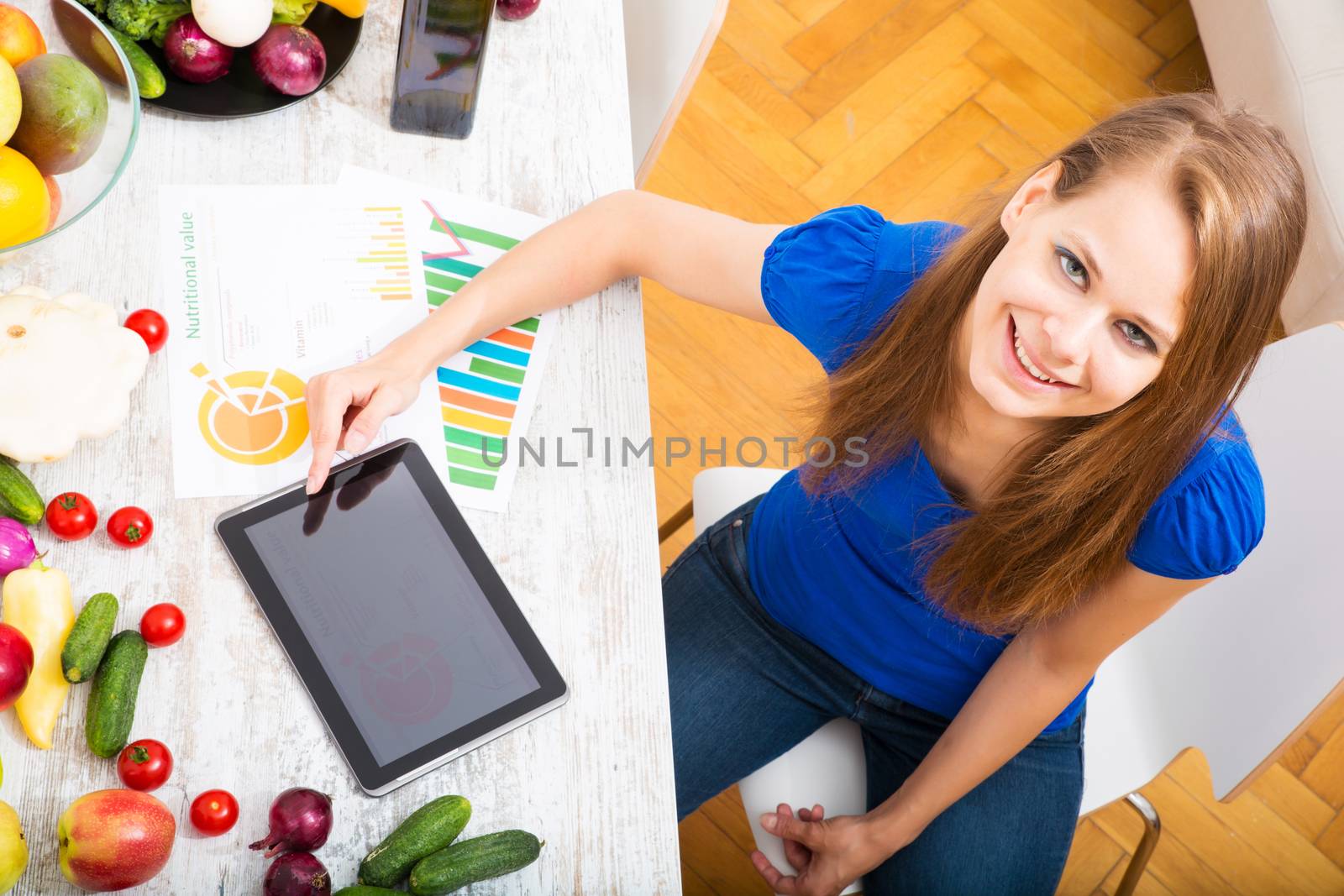 A young adult woman informing herself with a tablet PC about nutritional values of fruits and vegetables.
