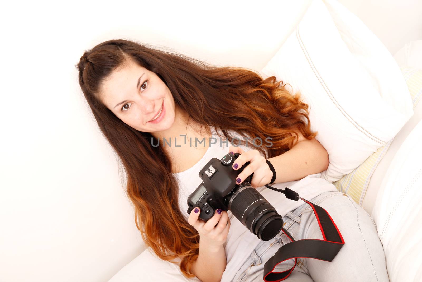 A young hispanic girl with DSLR camera in the bed. 
