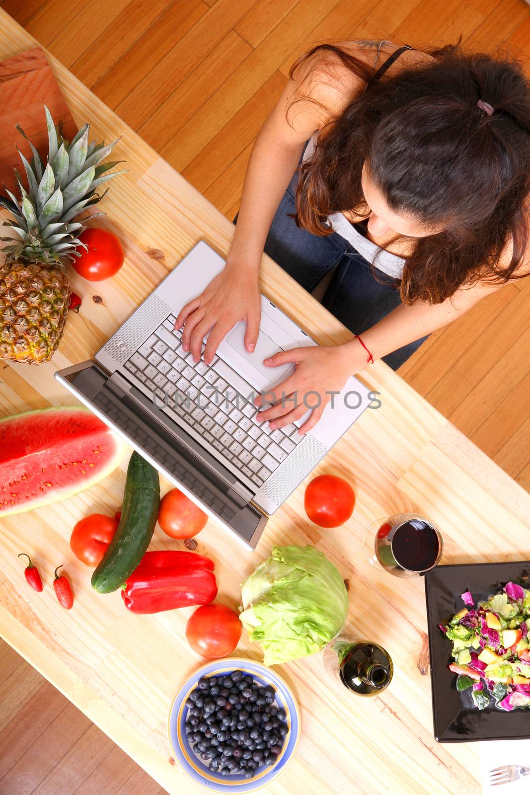 A young woman using a Laptop while cooking.