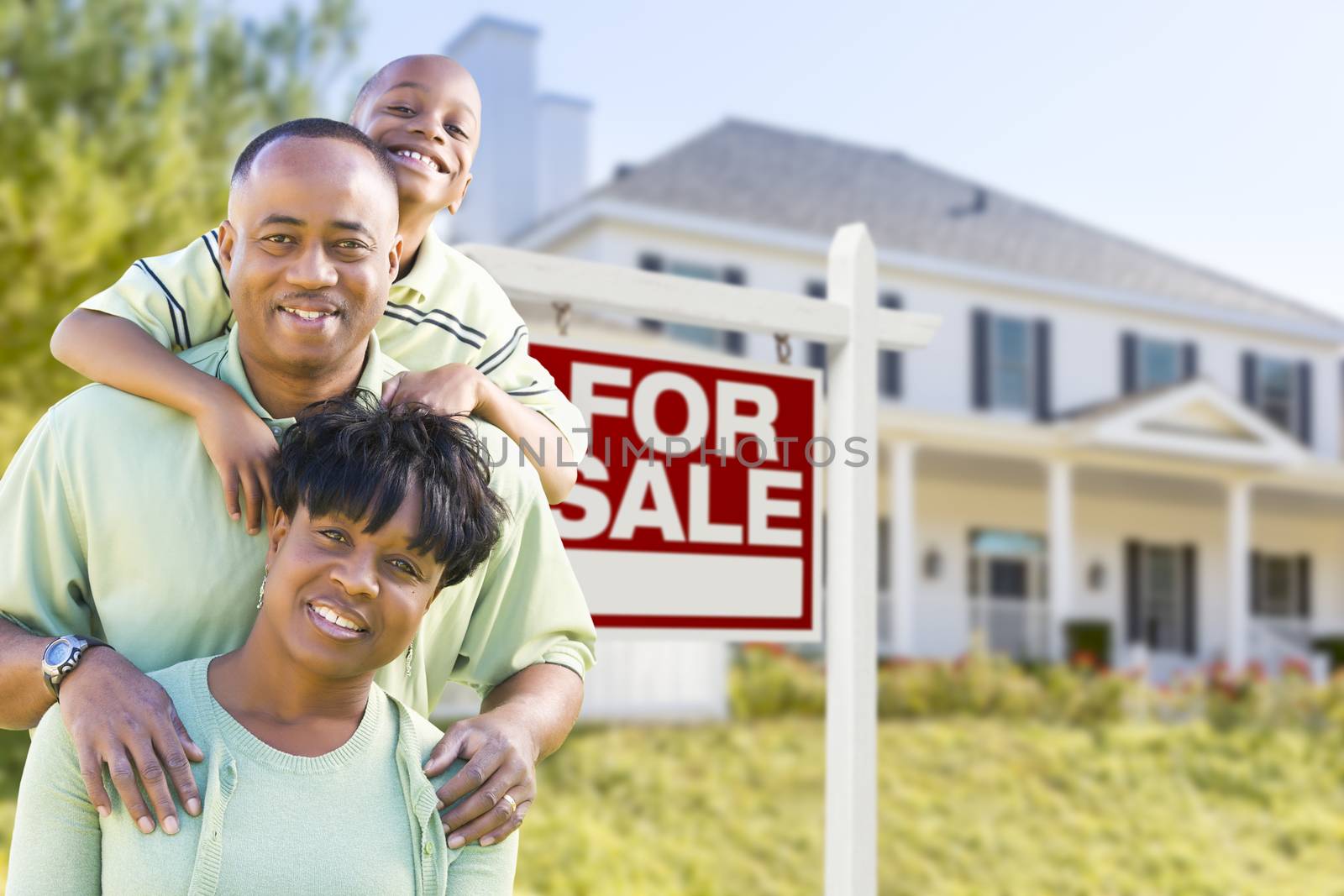 African American Family In Front of Sale Sign and House by Feverpitched