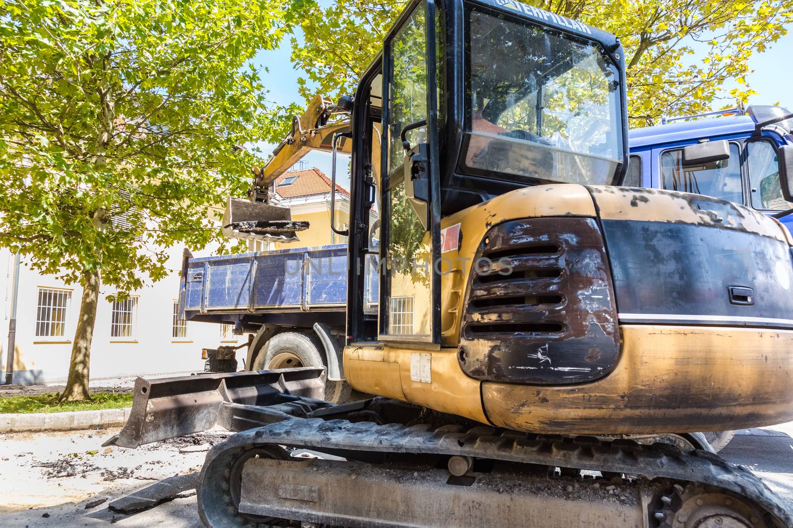 Excavator loading dumper truck with sand at construction site.