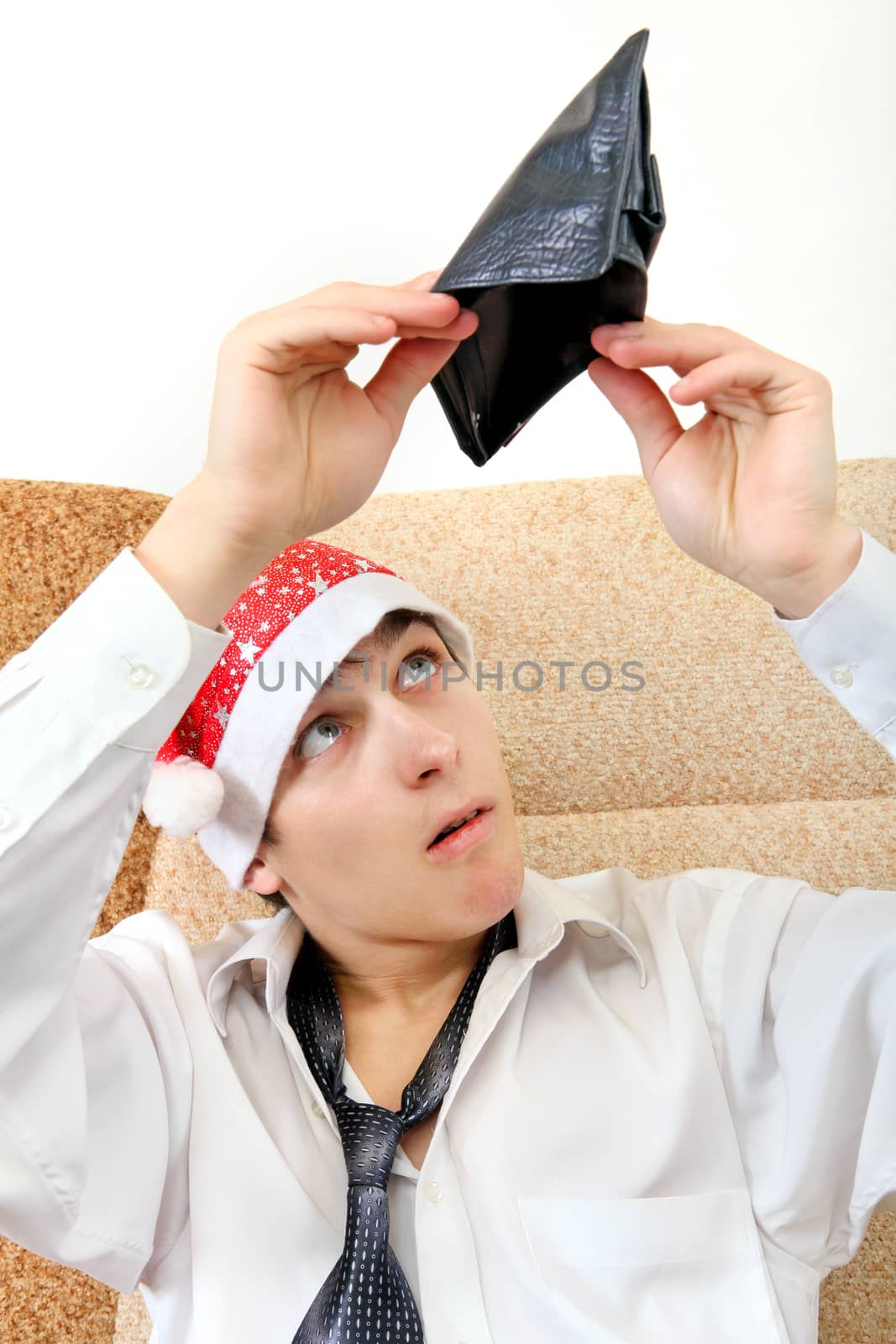 Teenager in Santa Hat Checking Empty Wallet on the Sofa at the Home