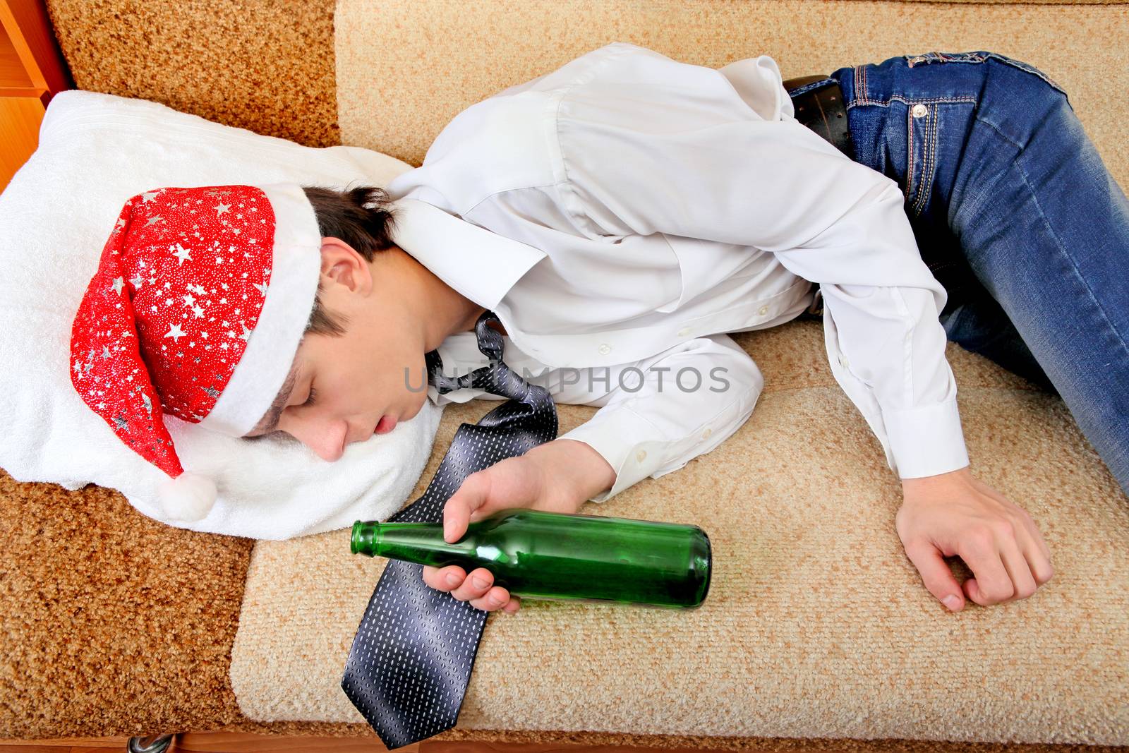 Drunken Teenager sleeping in Santa Hat and Bottle of the Beer on the Sofa