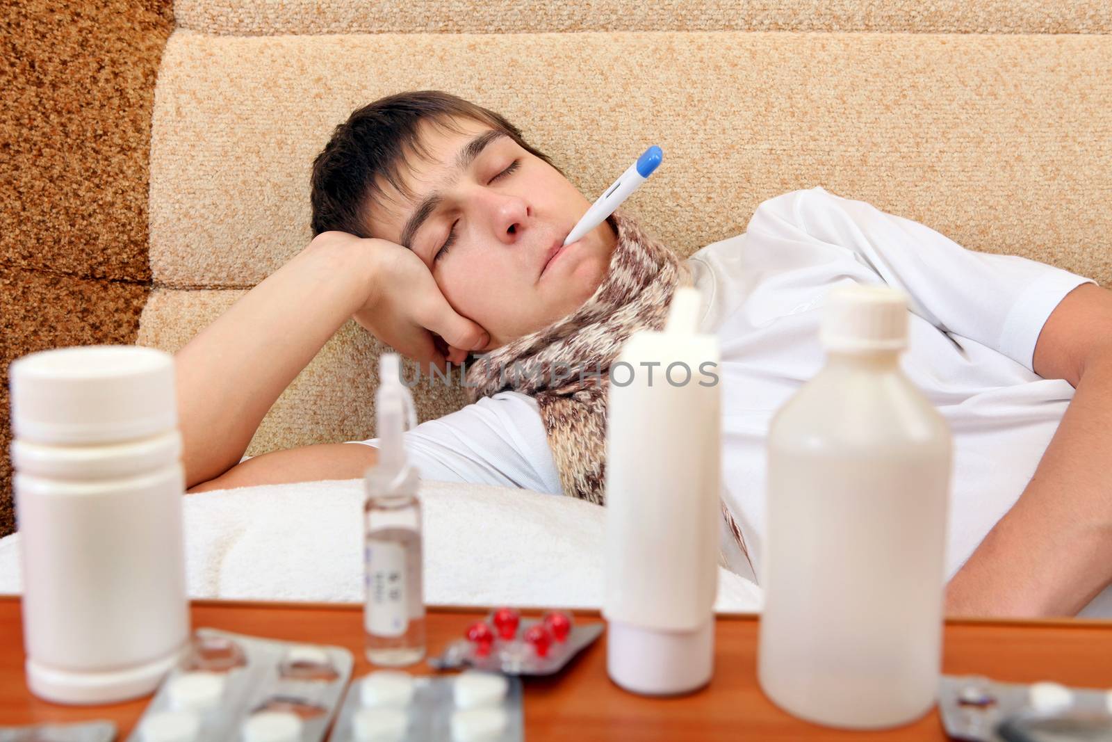 Sad and Sick Teenager on the Sofa at the Home with Pills on foreground