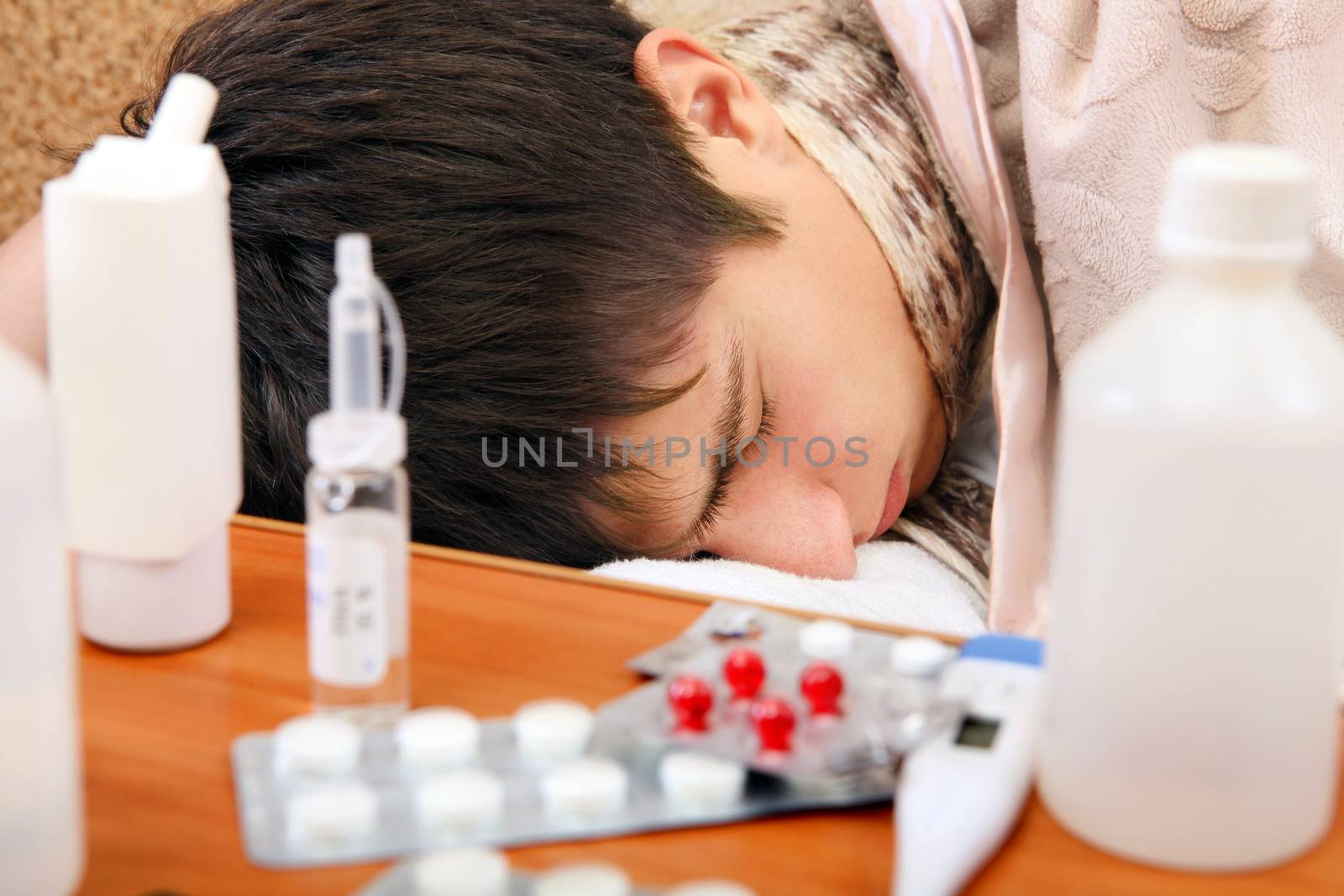 Sick Teenager sleeping on the Sofa with Pills on foreground