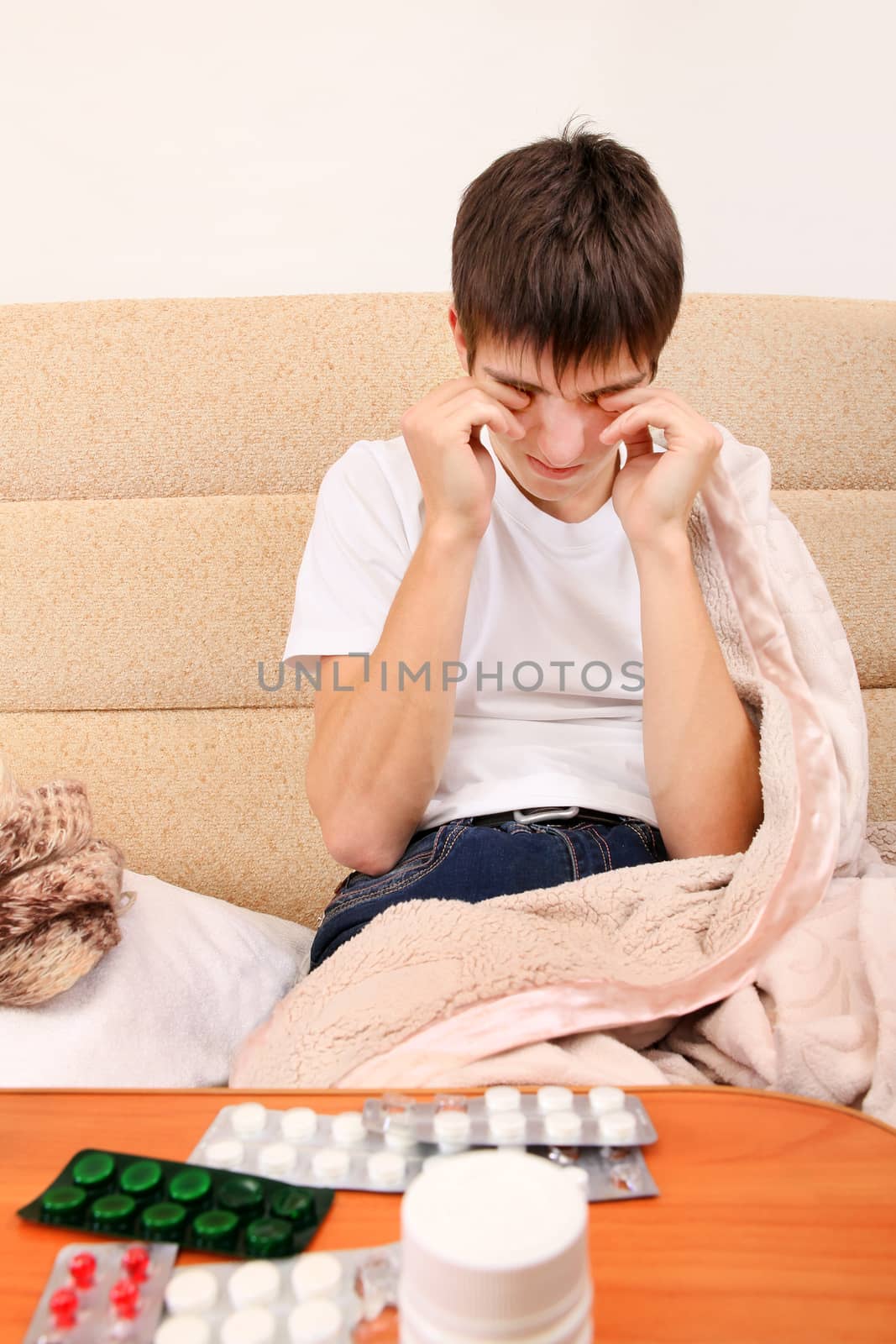 Sick and Tired Teenager on the Sofa at the Home with Pills on foreground