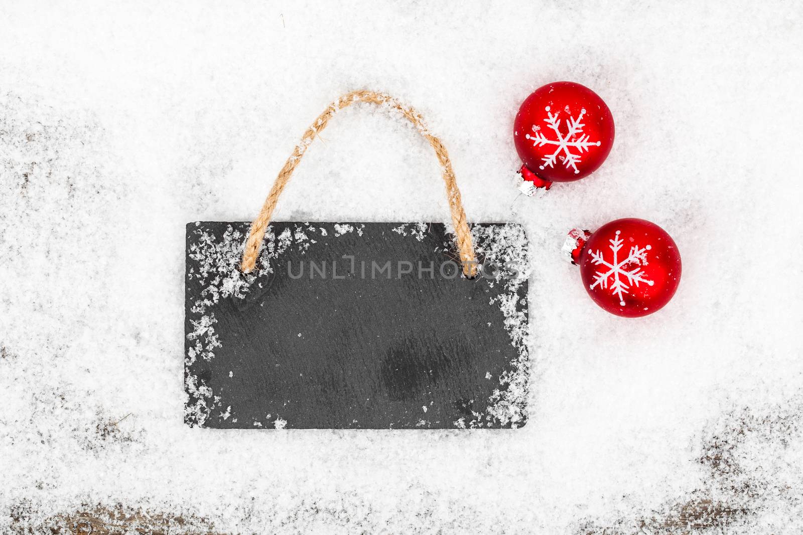 Black board of slate on rustic wooden background with snow