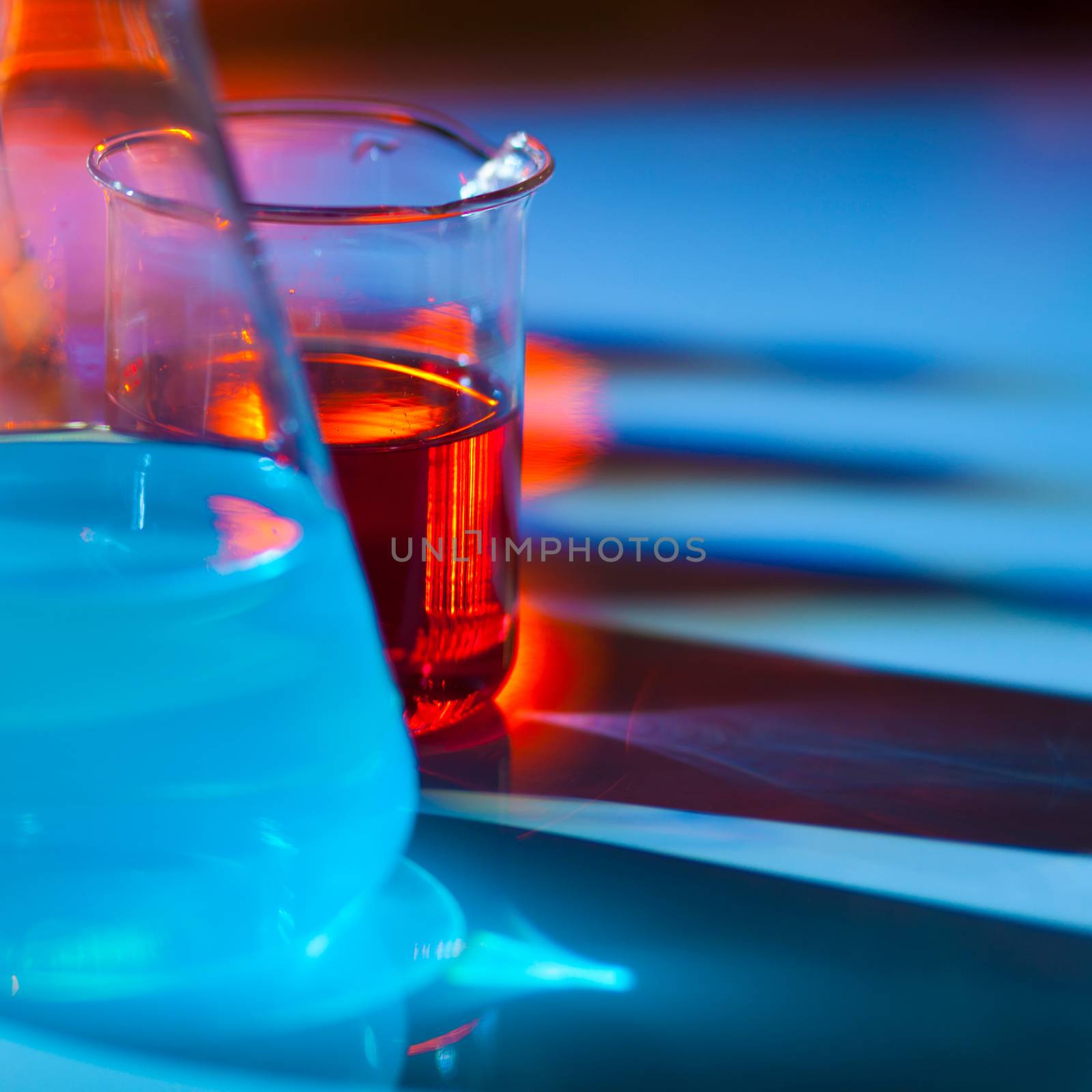 Backlit laboratory test flask containing colorful liquids.