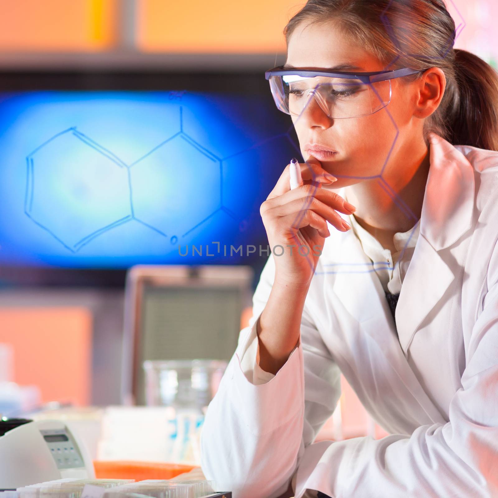 Portrait of a confident female health care professional in his working environment reviewing structural chemical formula written on a glass board.