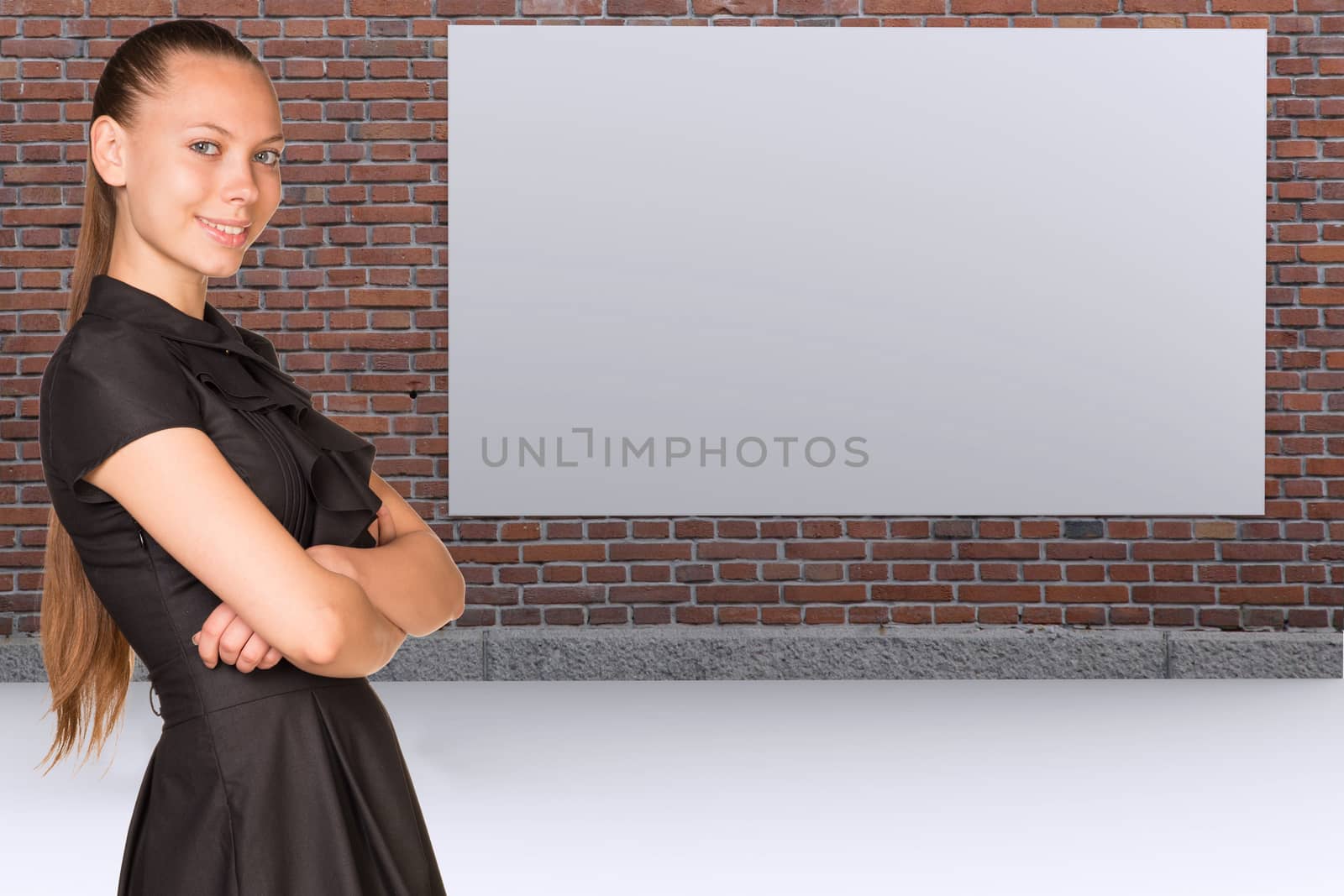 Beautiful businesswoman in dress smiling and looking at camera. Brick wall with empty white placard as backdrop. Business concept