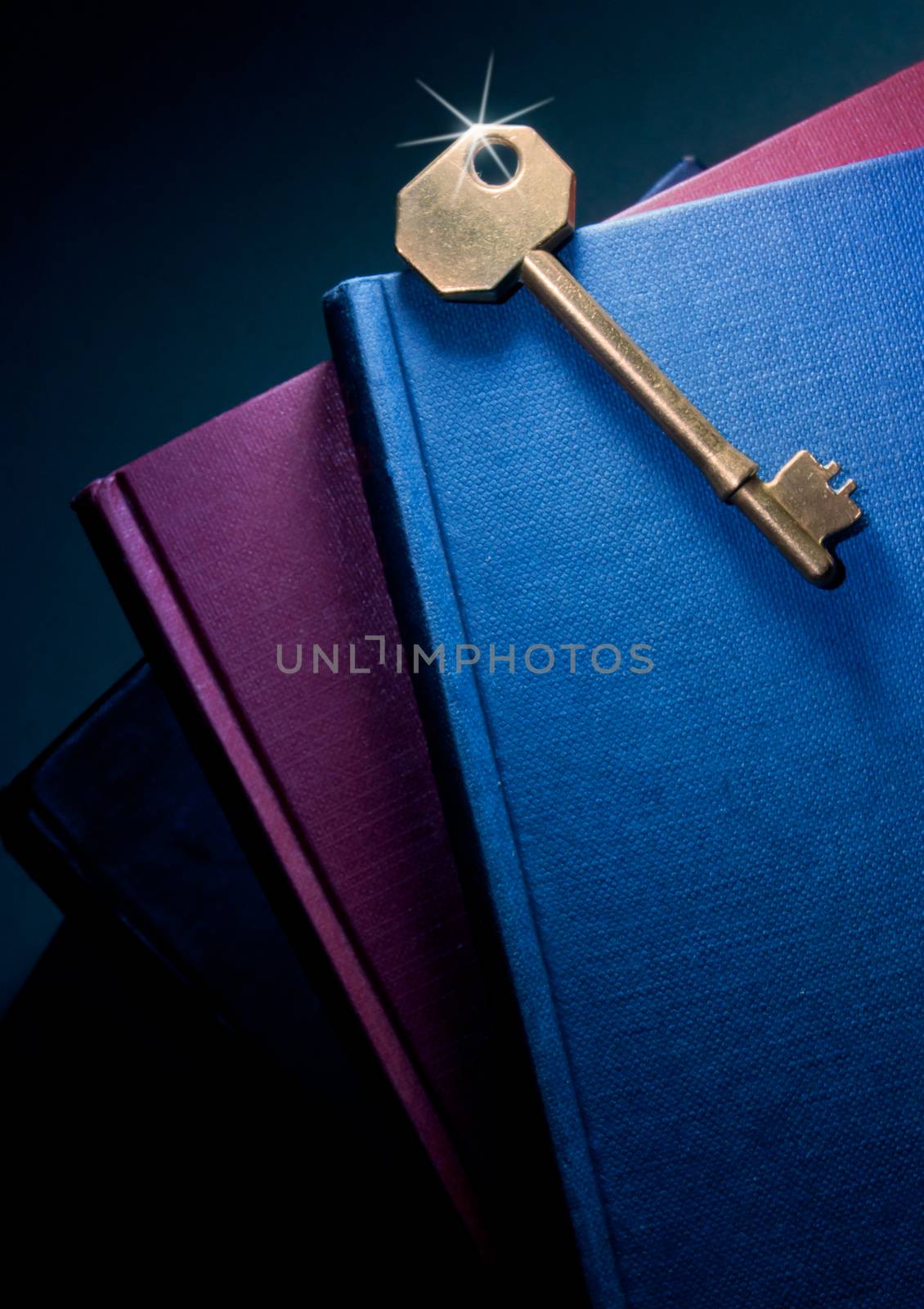 Stack of books with shiny gold key on top symbolising knowledge