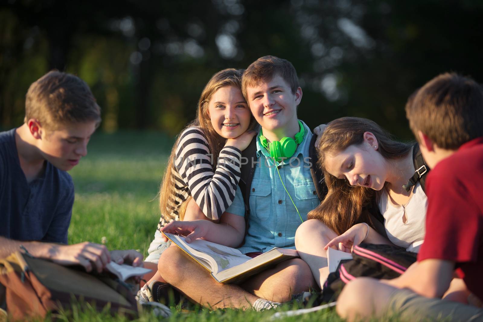 Happy girl leaning on boyfriends shoulders with friends outdoors