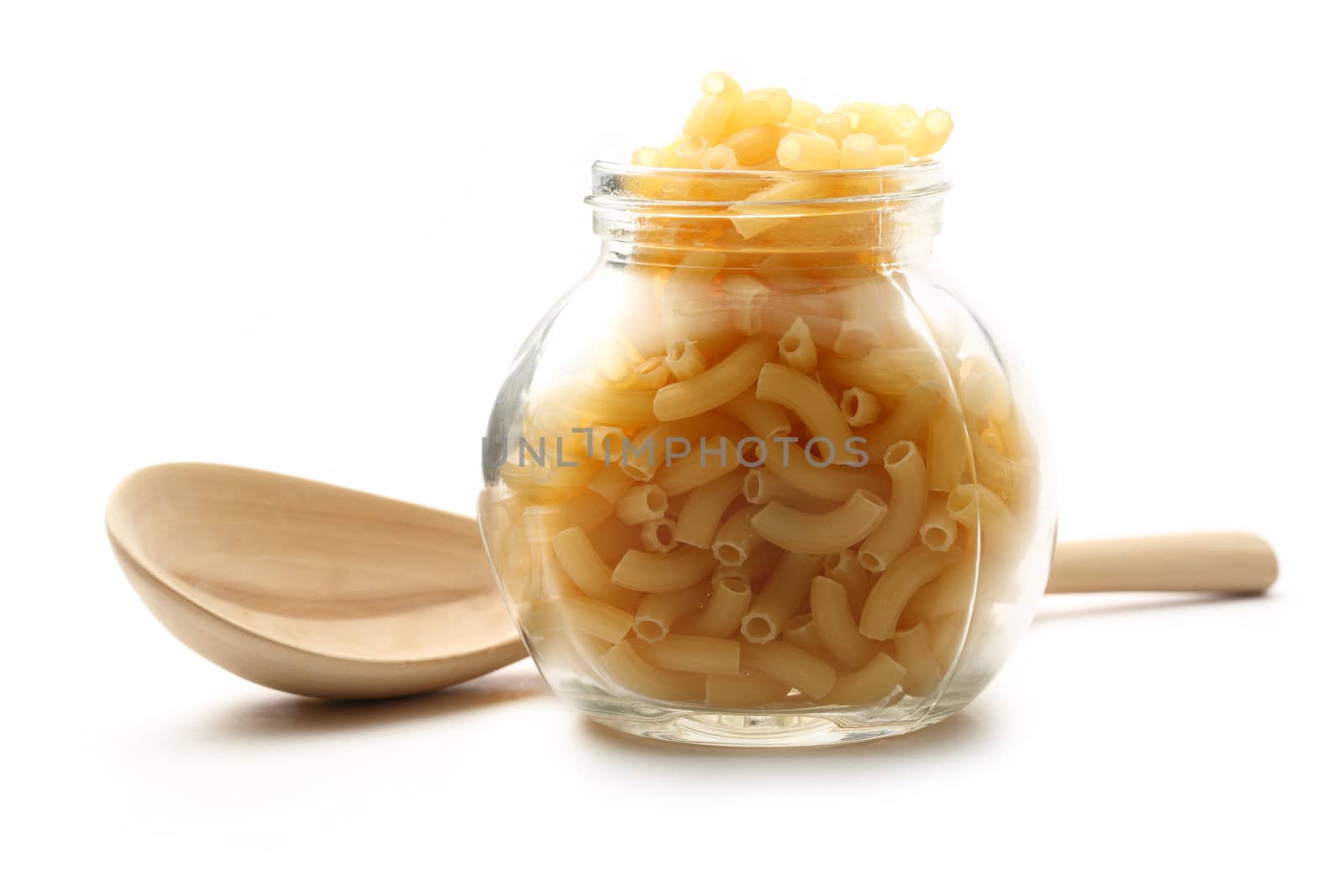Short ribbed pasta tubes in jar and wooden spoon