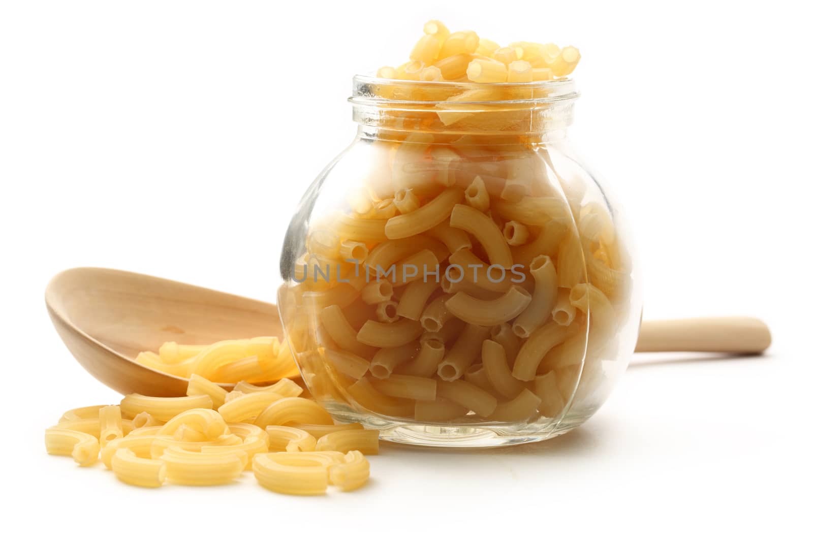 Short ribbed pasta tubes in jar and wooden spoon