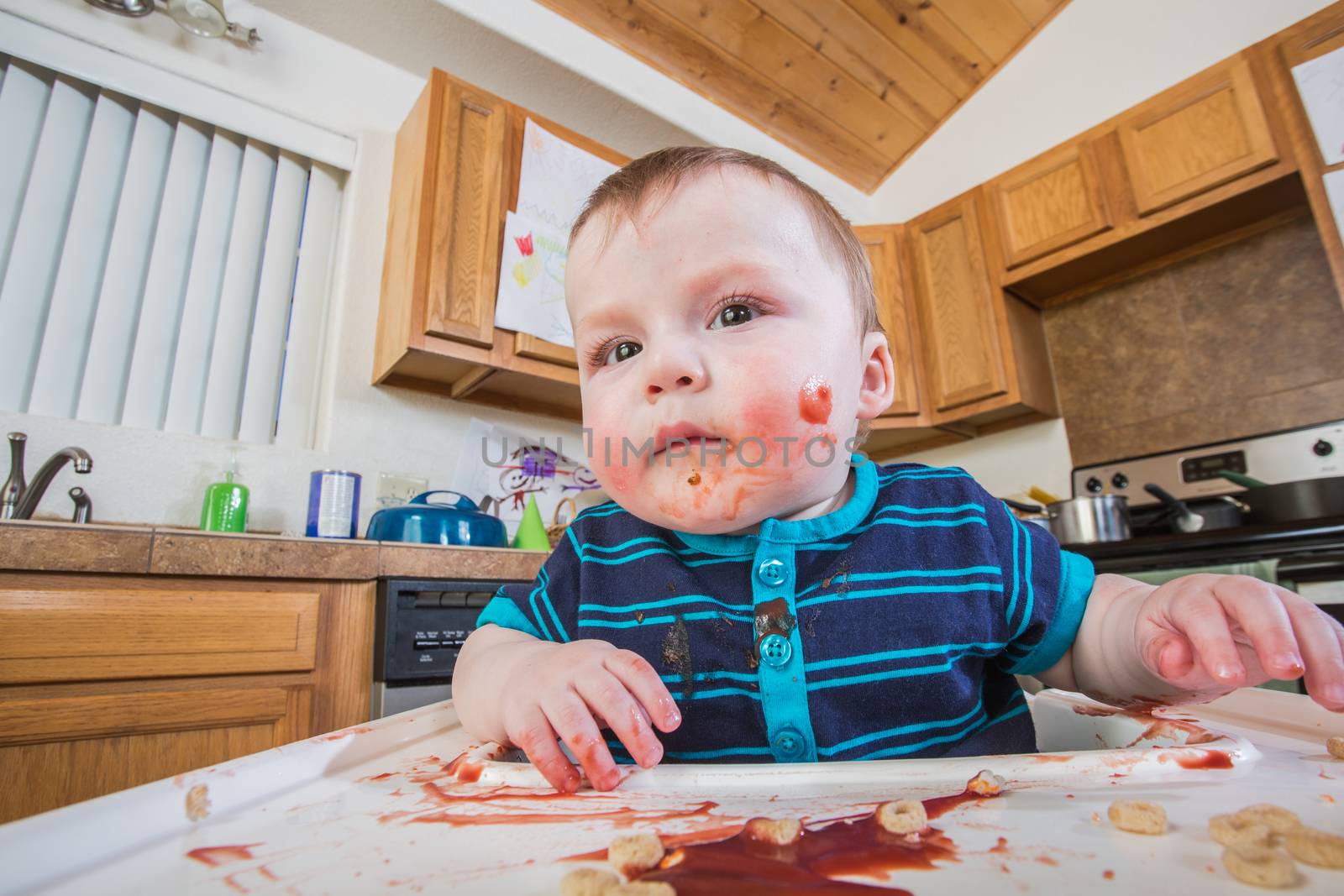 A messy child eats breakfast in the kitchen