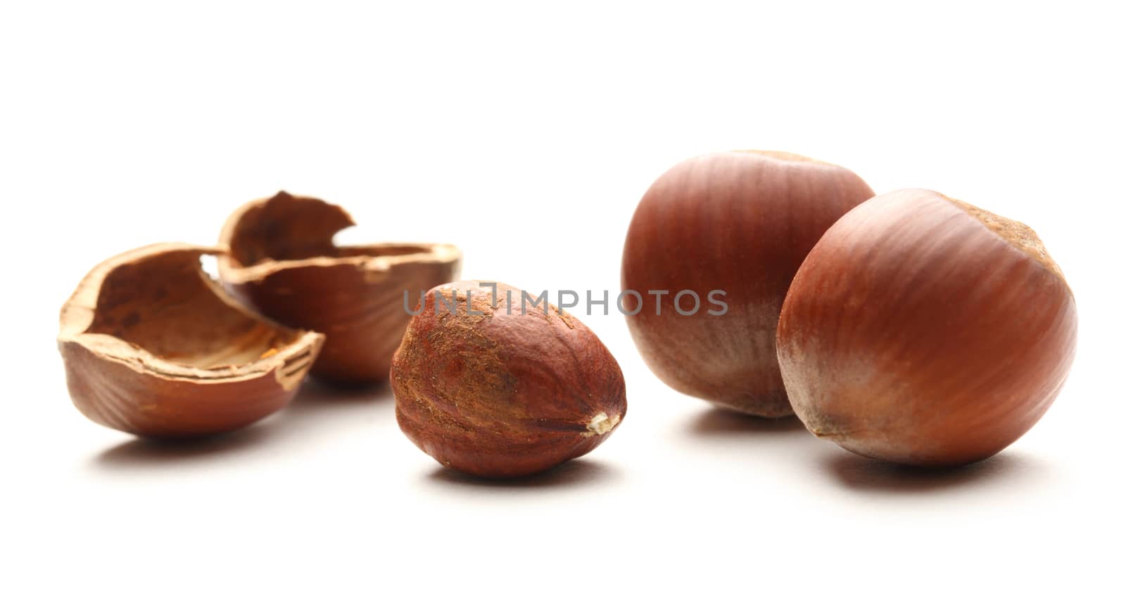 Whole and cracked hazelnuts on white