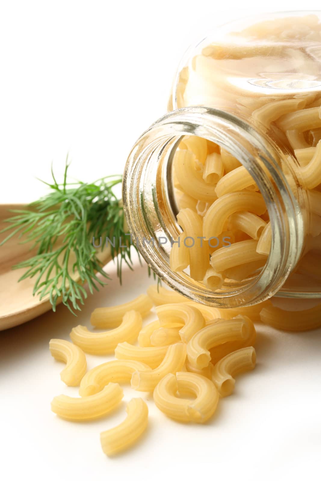 Short ribbed pasta tubes in jar and wooden spoon