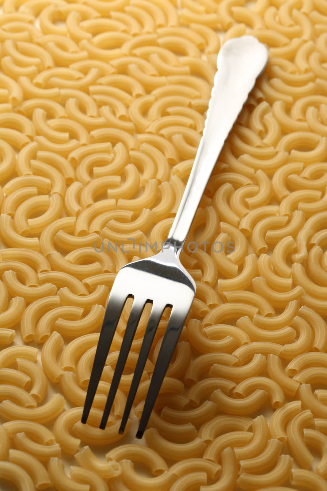 Short ribbed pasta tubes background with fork