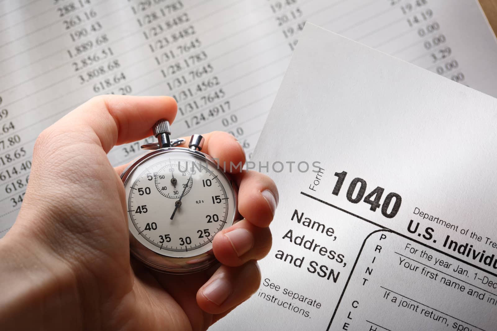Hand with stopwatch on tax form and budget