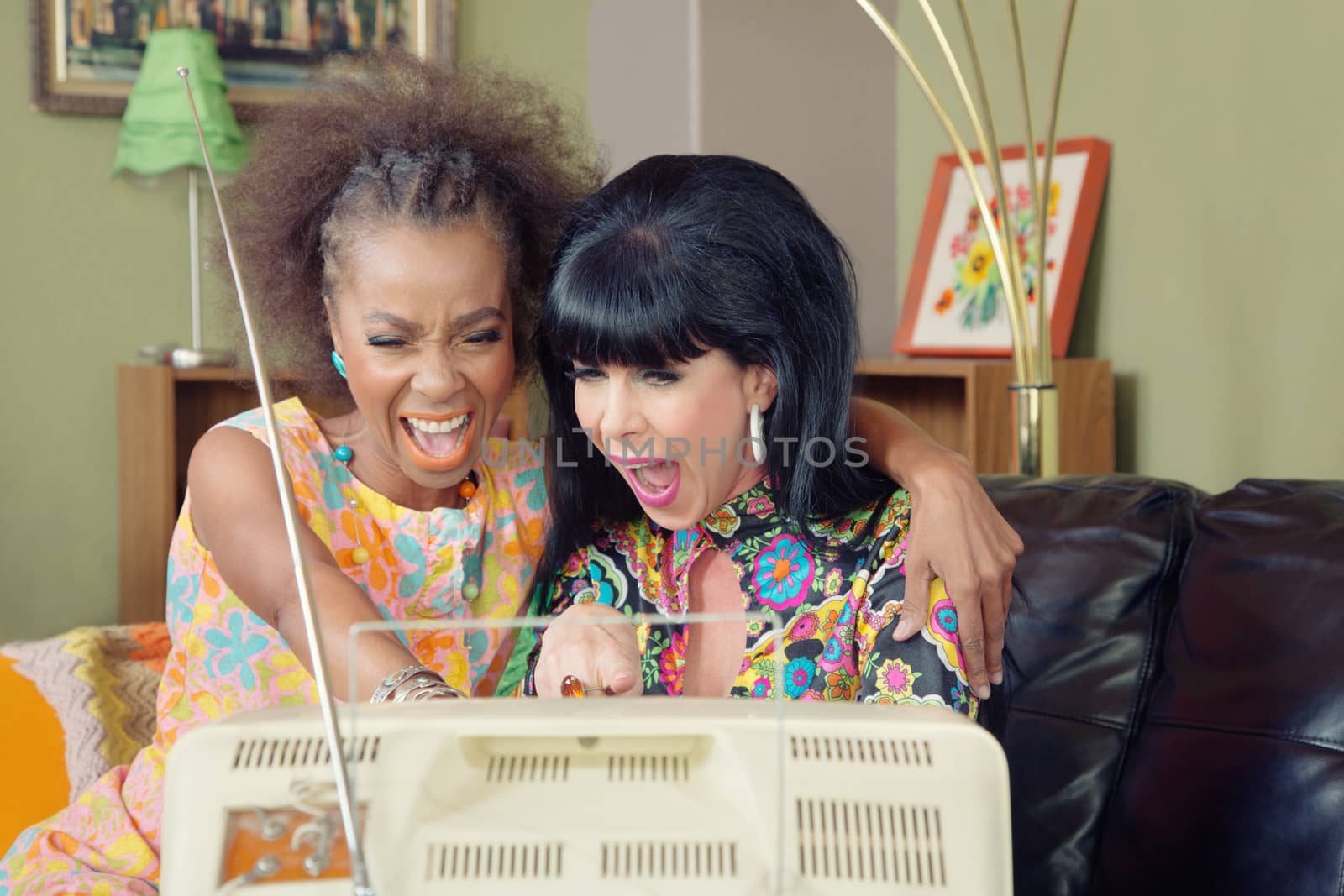 Mixed pair of friends laughing together in front of television