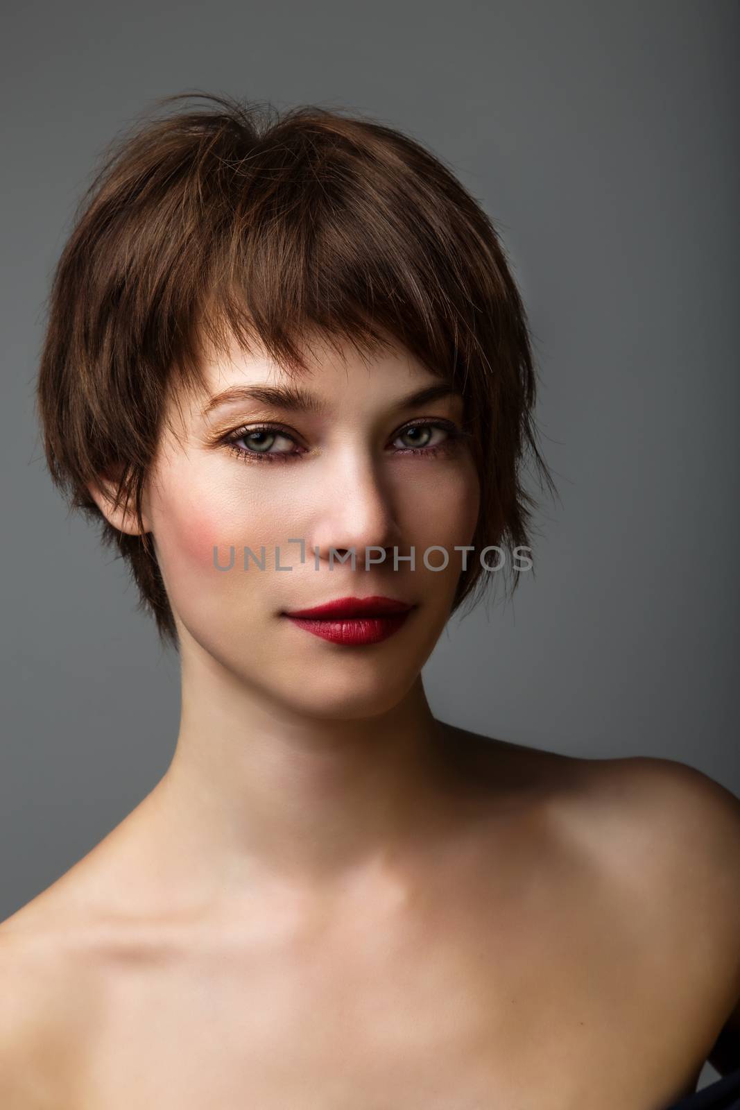 Side portrait of a young woman with short brown hair and brown glowing eyes