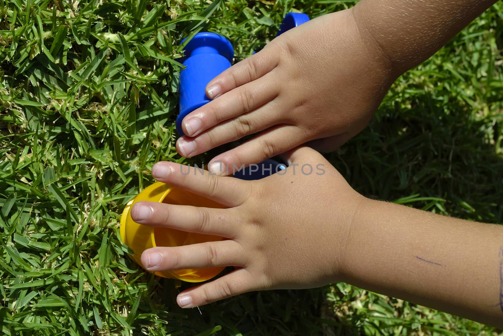 Hands of a child playing with plastic cups by ncuisinier