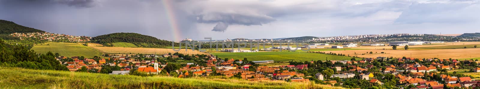 Landscape with Several Populated Areas under Cloudy Sky and Rainbow