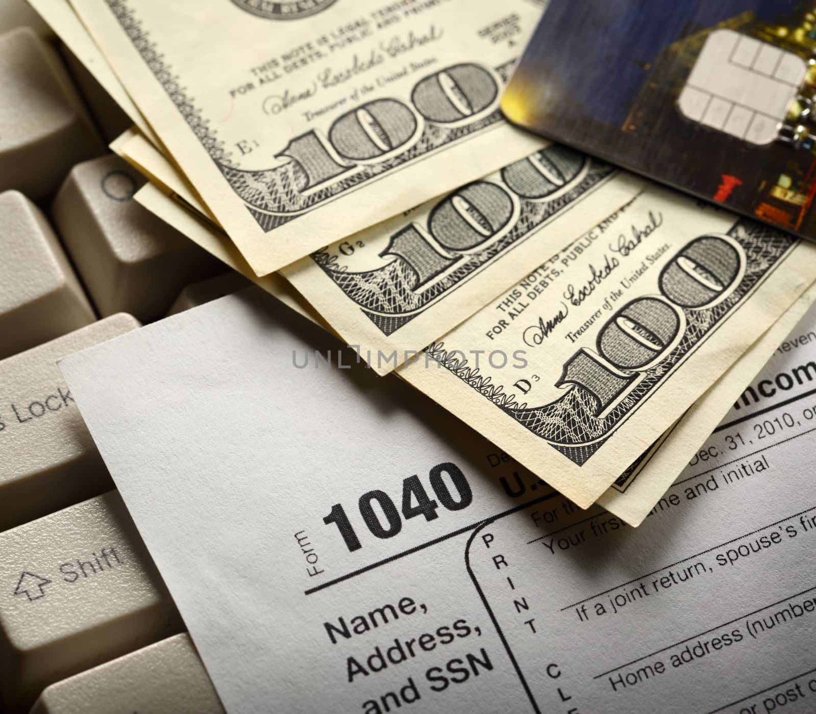 Computer keyboard, credit cards, tax form and dollars in cash