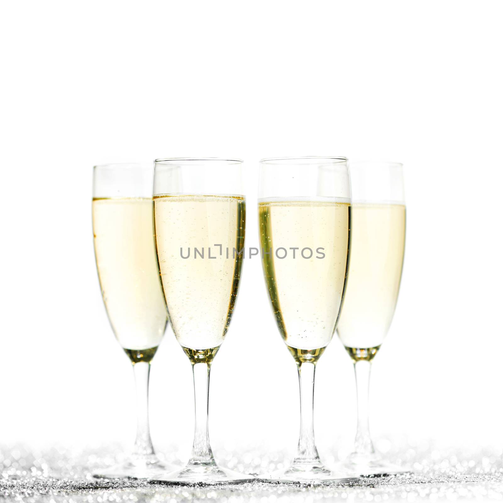 Glasses of champagne on glitters isolated on white background