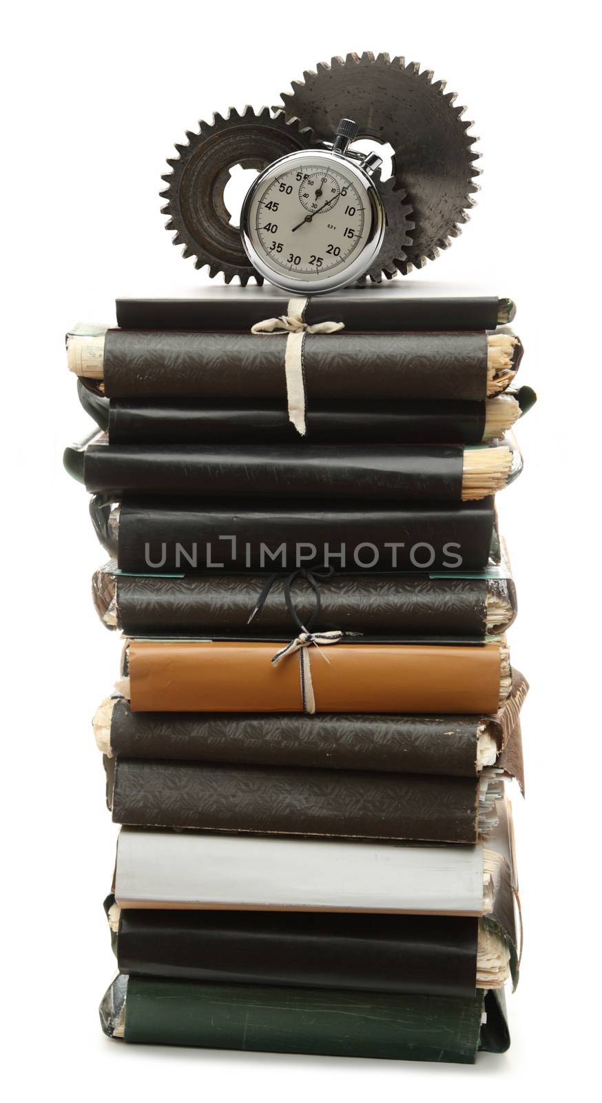 Steel cogwheels, stopwatch on stack of old paper folders