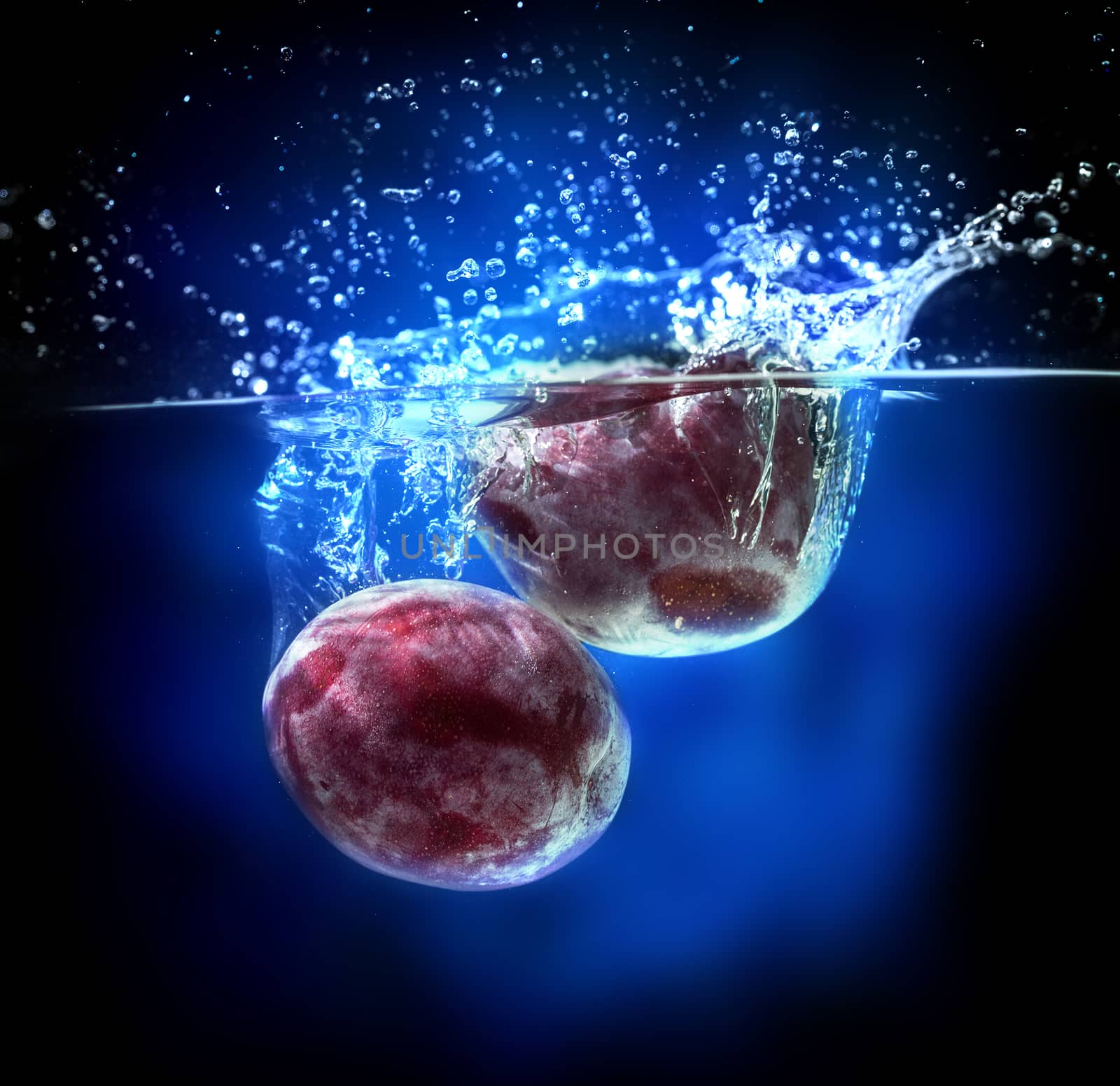 Fresh plums in water splash