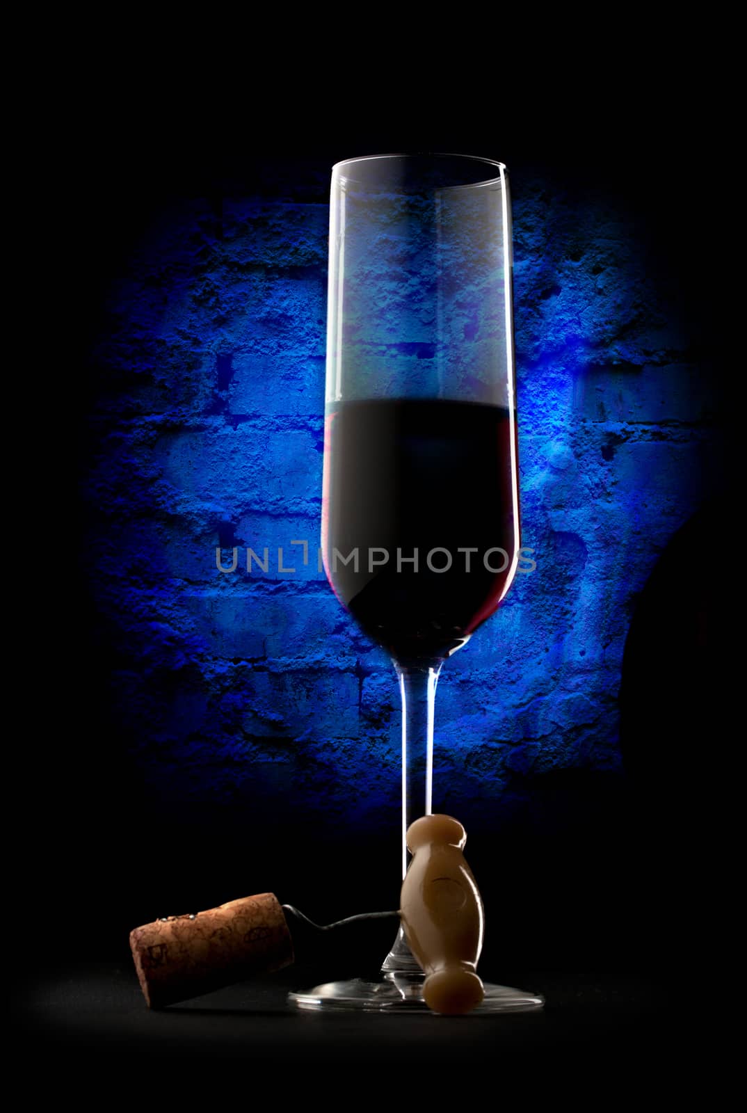 Glass of red wine with corkscrew on wall background