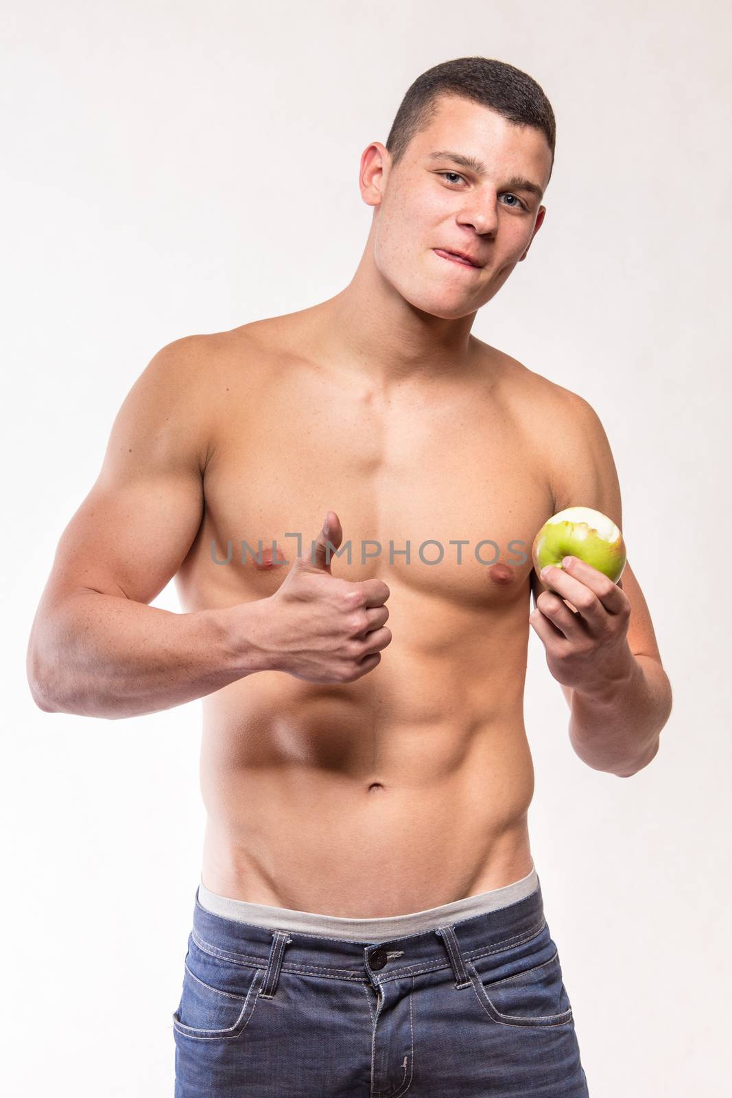 Muscular fitness man with apple showing OK sign - studio shoot 