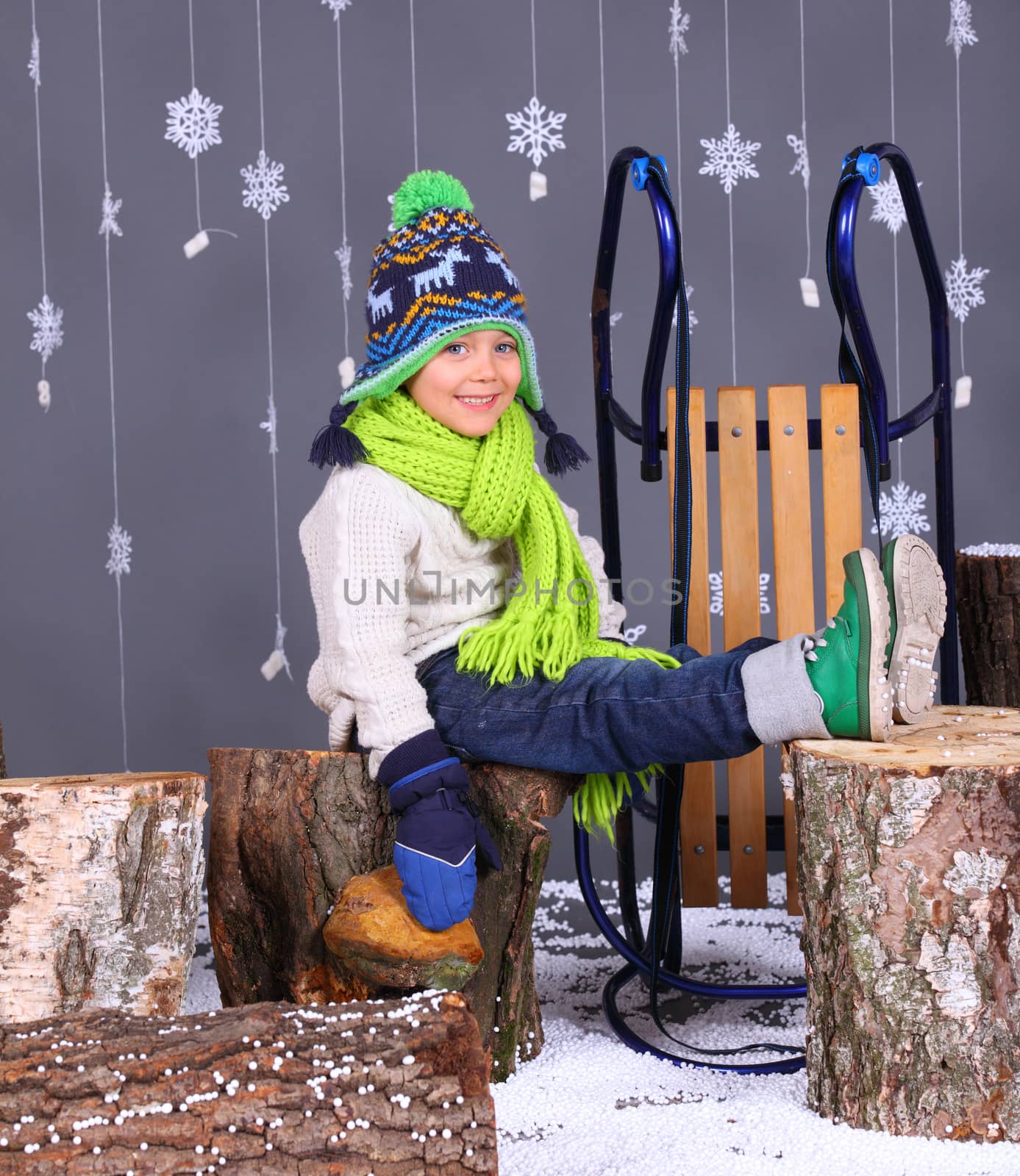 Winter Fashion. Portrait of adorable happy boy in winter hat, gloves and sweater in studio.