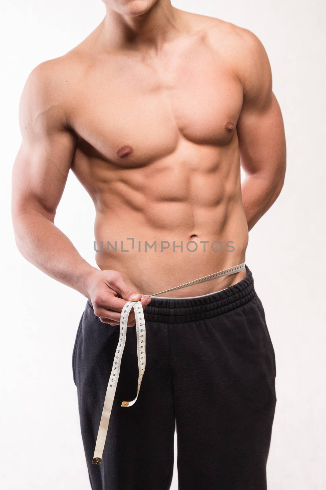 Muscular fitness man measuring his waist - studio shoot 